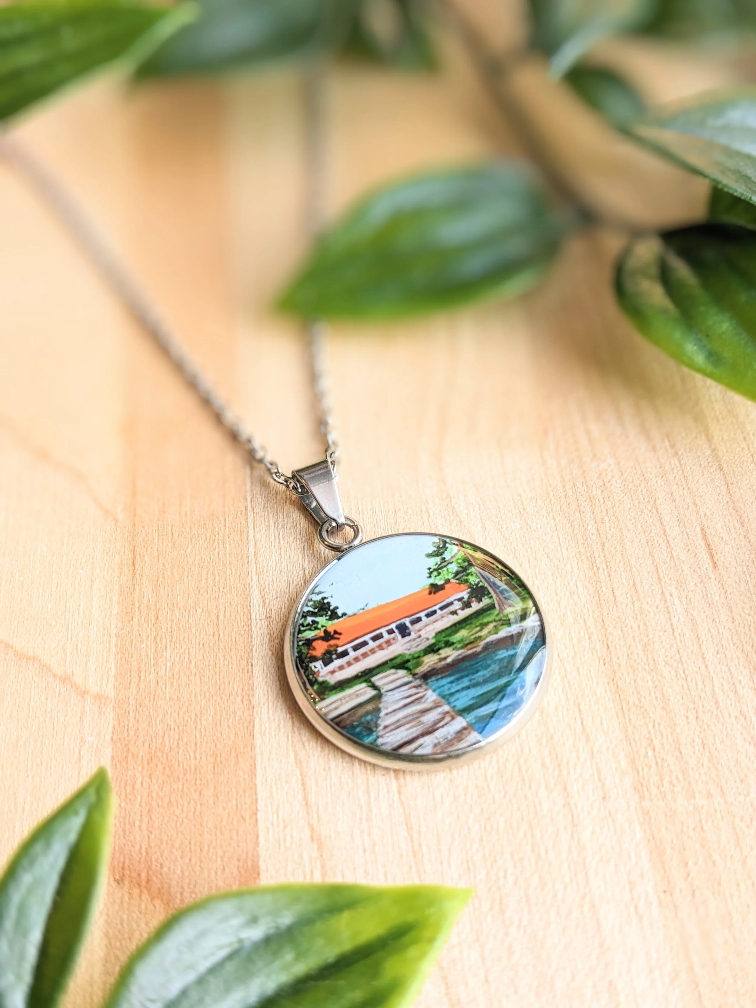 Custom hand-painted necklace featuring a lakeside cottage (2022)