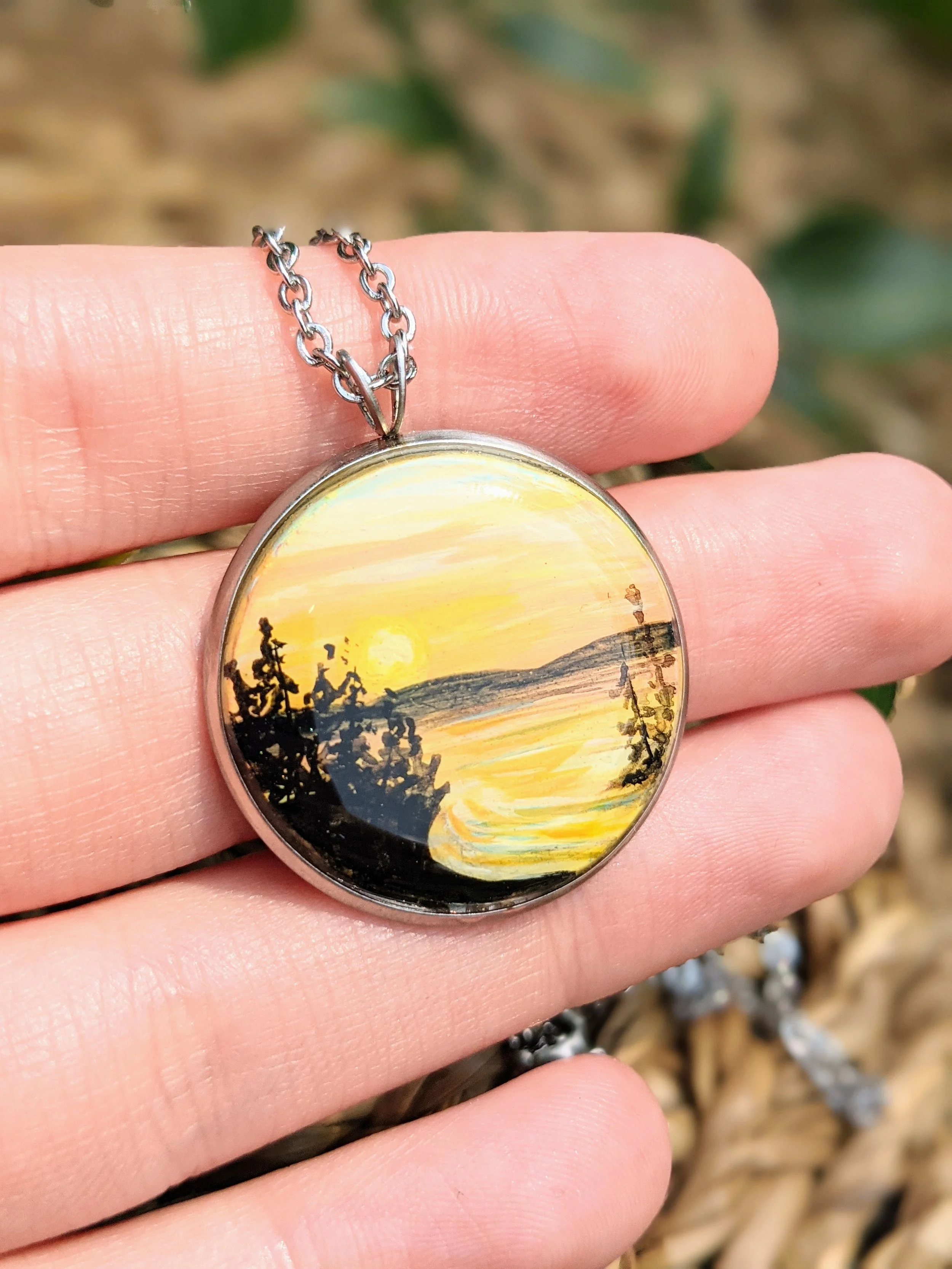 Custom hand-painted necklace featuring a lake at sunset (2022)