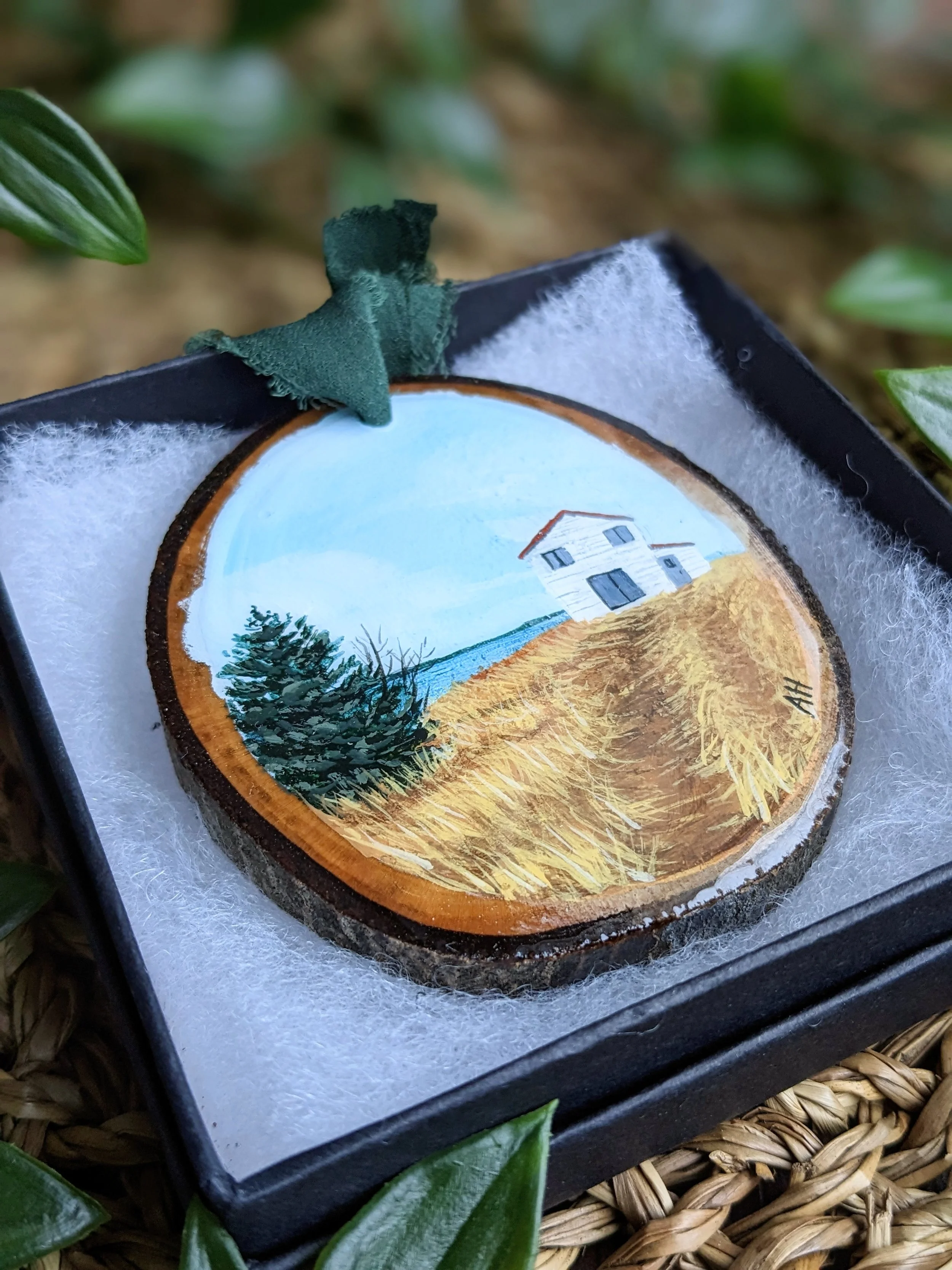 Custom hand-painted Christmas ornament featuring a white house along a rocky shoreline (2023)