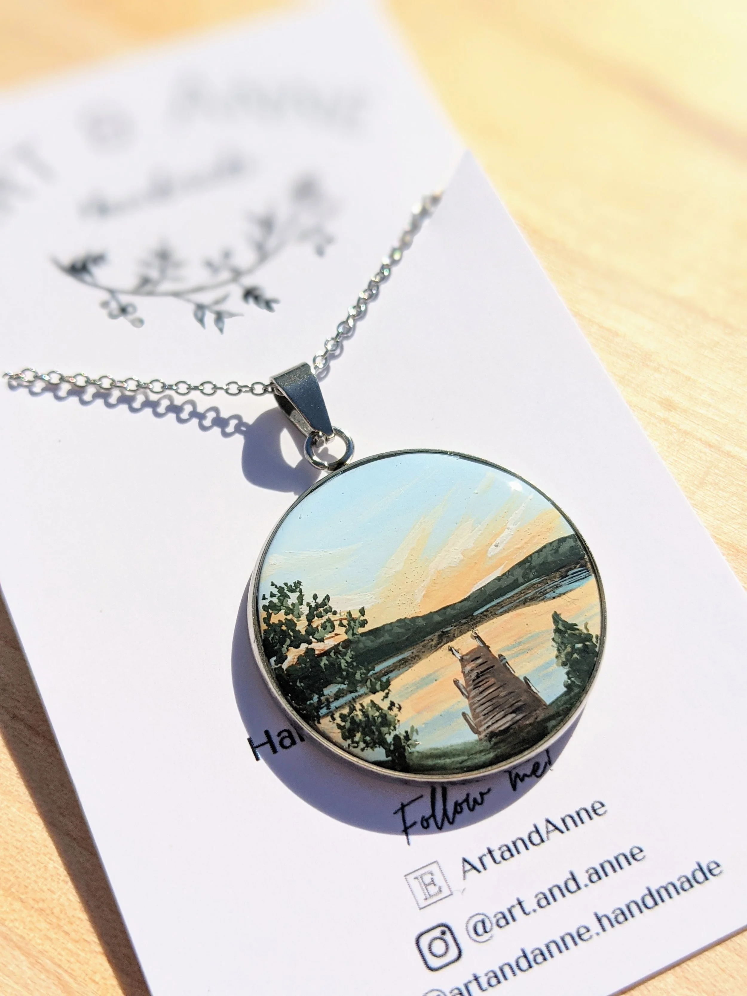 Custom hand-painted necklace featuring a lakeside dock at sunset (2022)