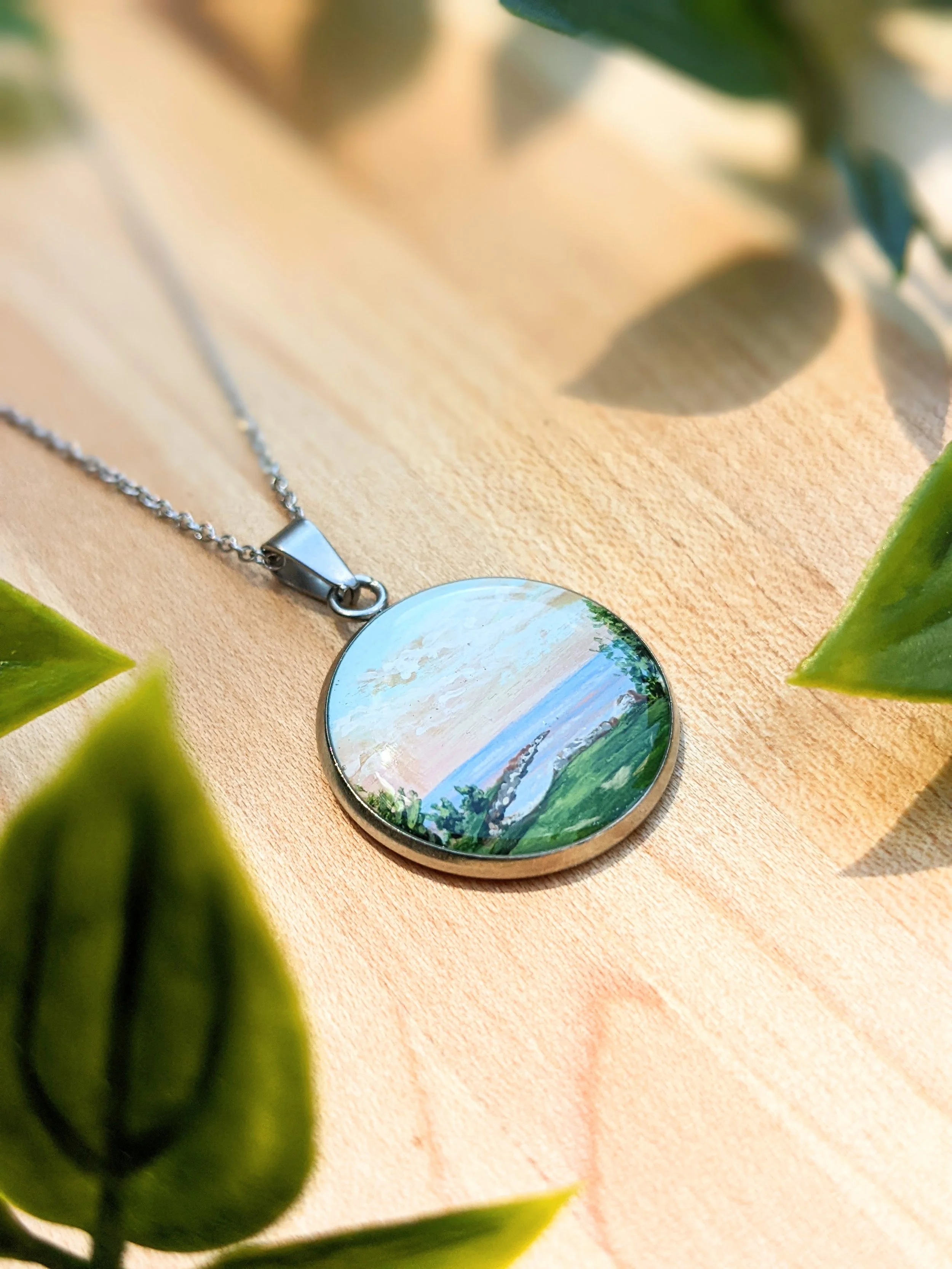Custom hand-painted necklace featuring a dock at sunset (2022)