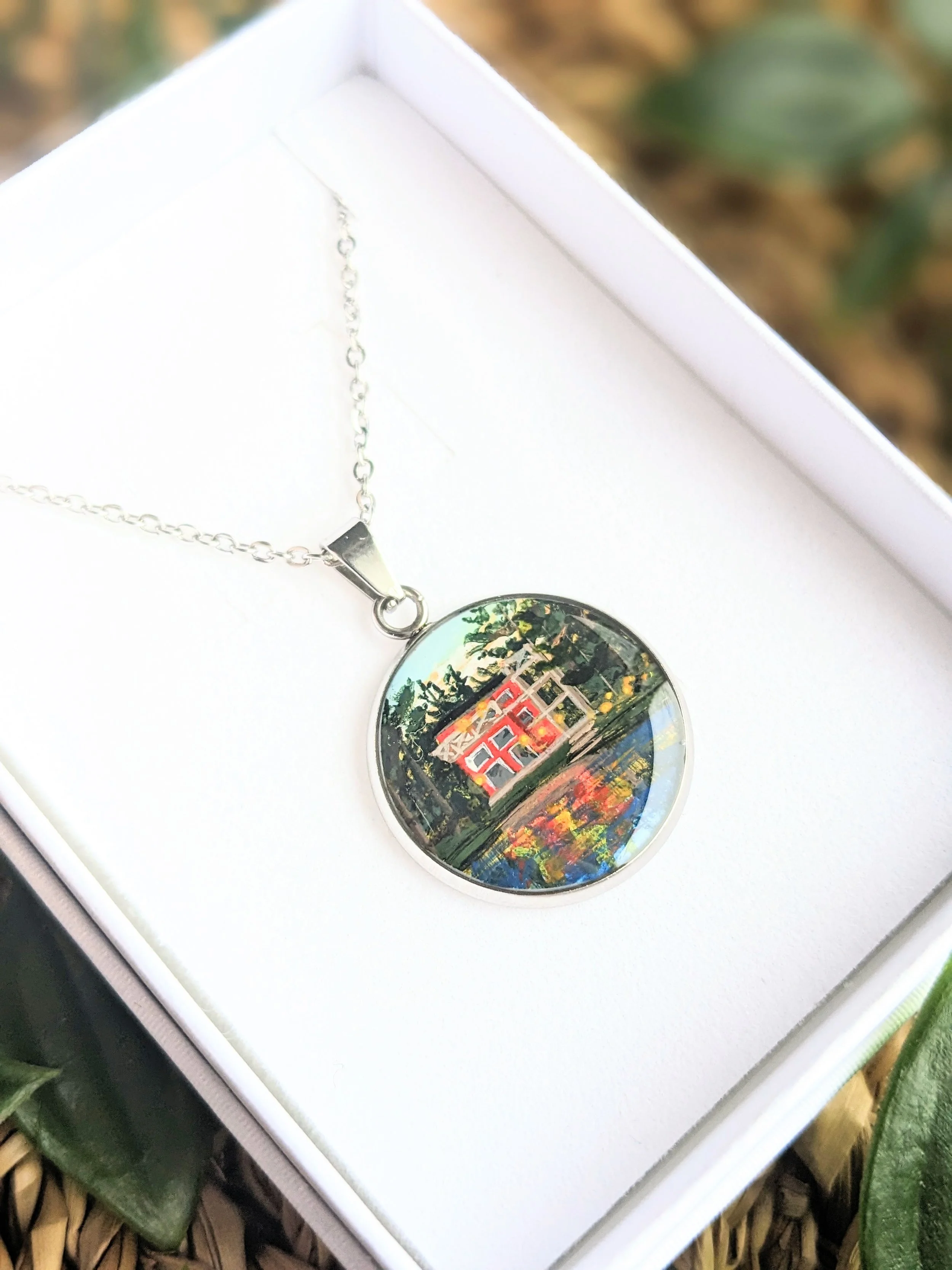 Custom hand-painted necklace featuring a red lakeside cottage (2023)