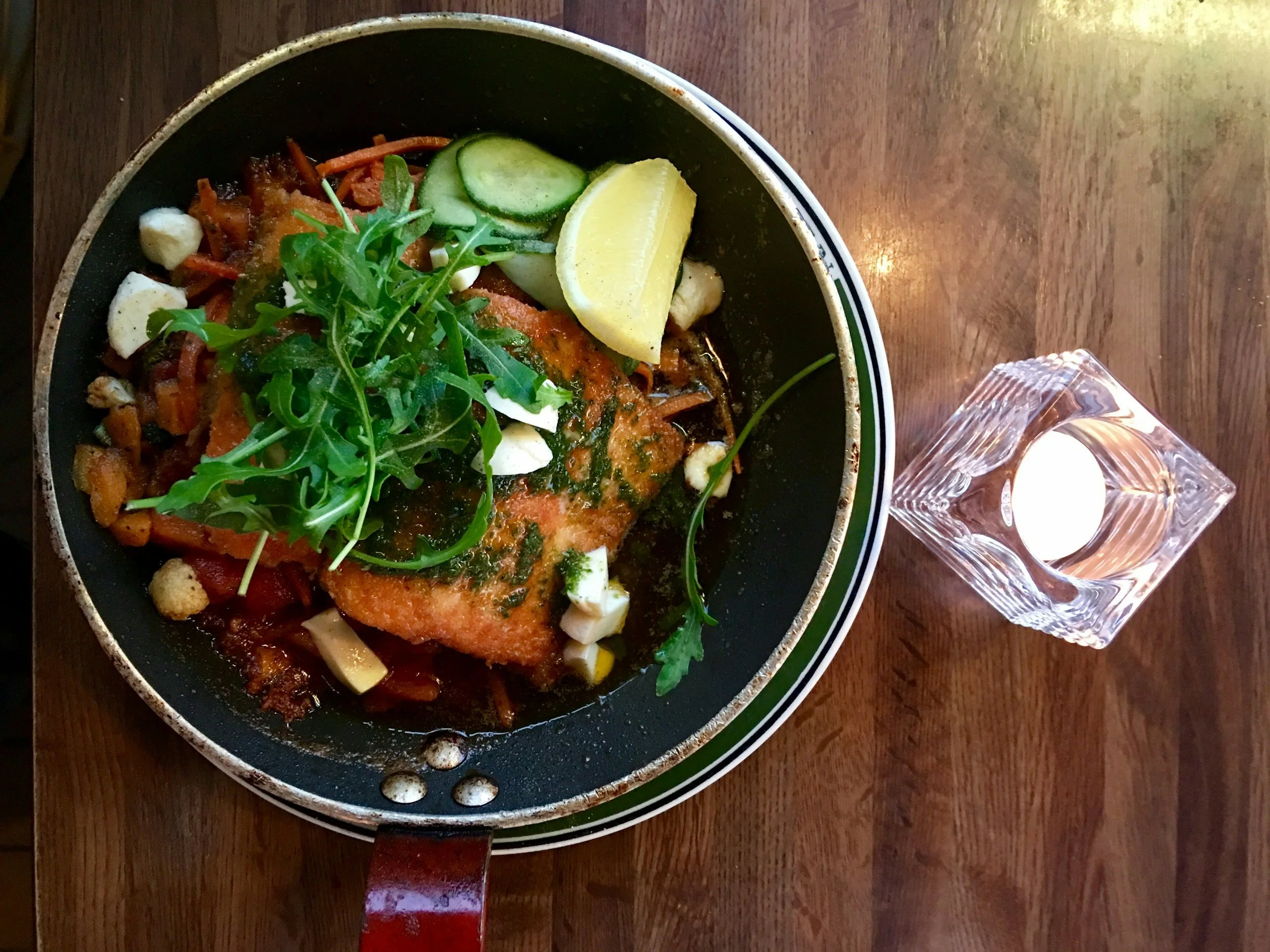 Three cooked lamb shanks on a wooden cutting board, garnished with fresh herbs.