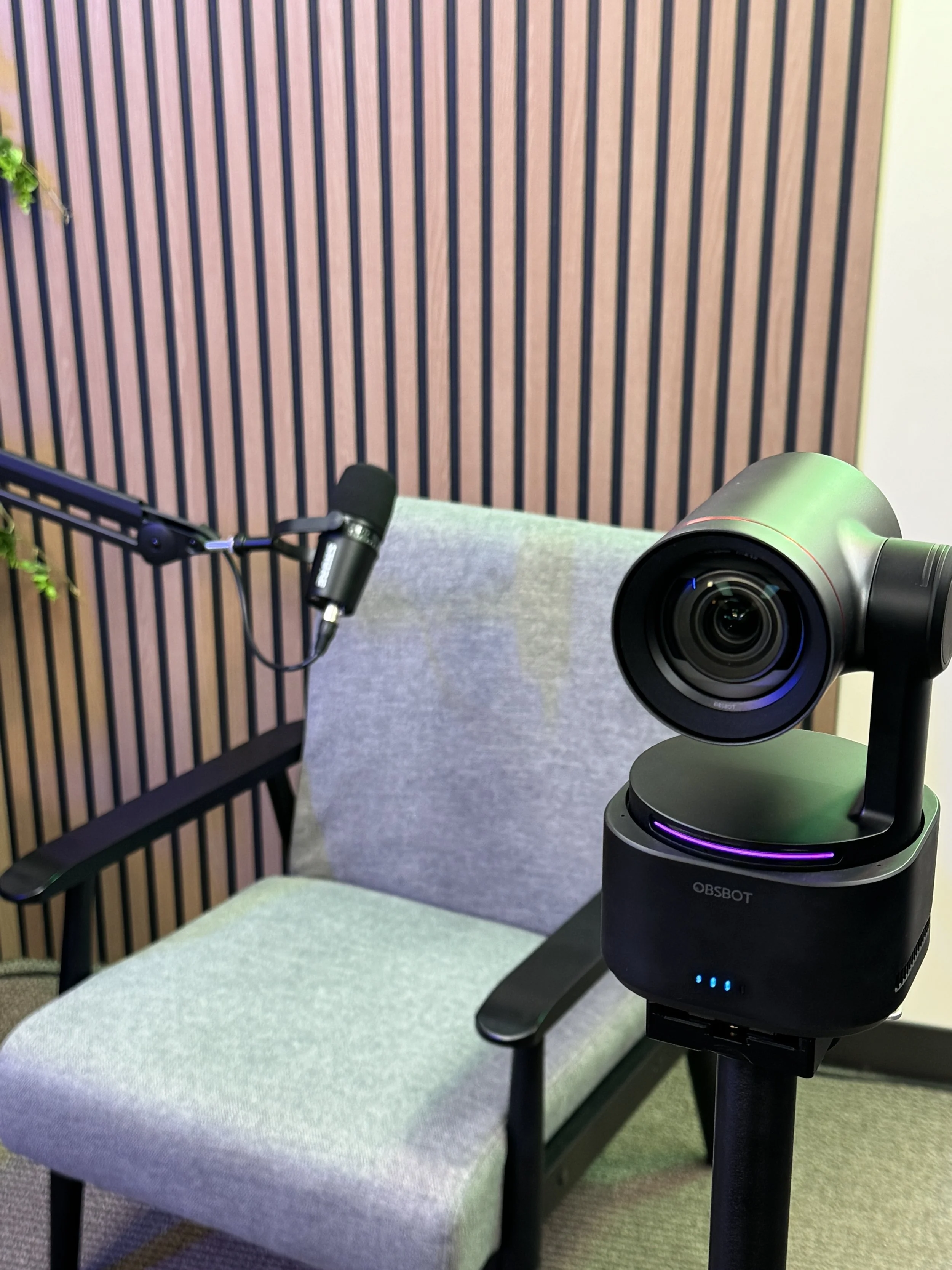 Professional video podcast studio featuring a PTZ camera, studio microphone, interview seating, and acoustic wall treatment at HLE Pro on the Big Island of Hawaii.