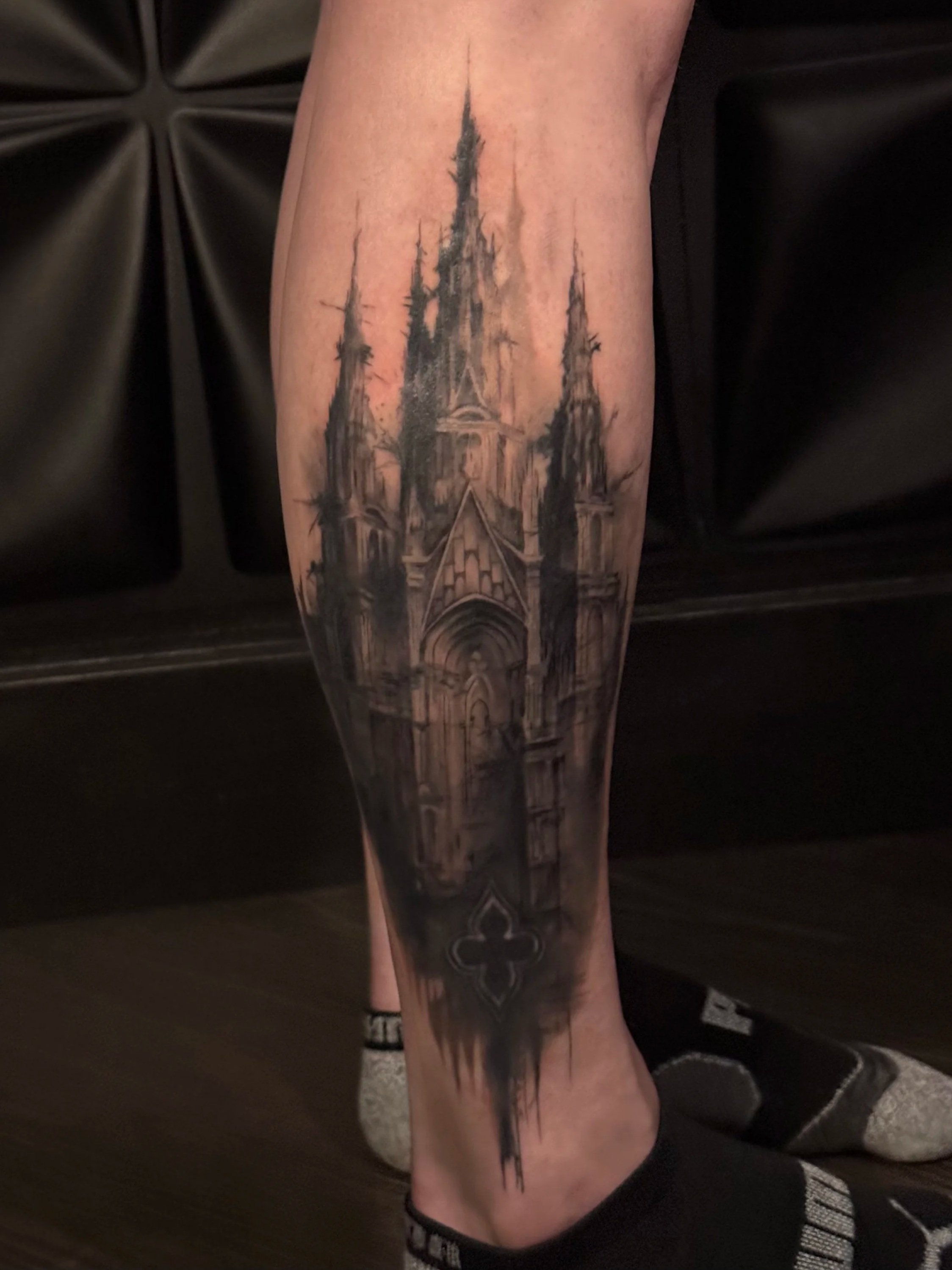 Tattoo of a Gothic castle with tall spires on a person's calf.