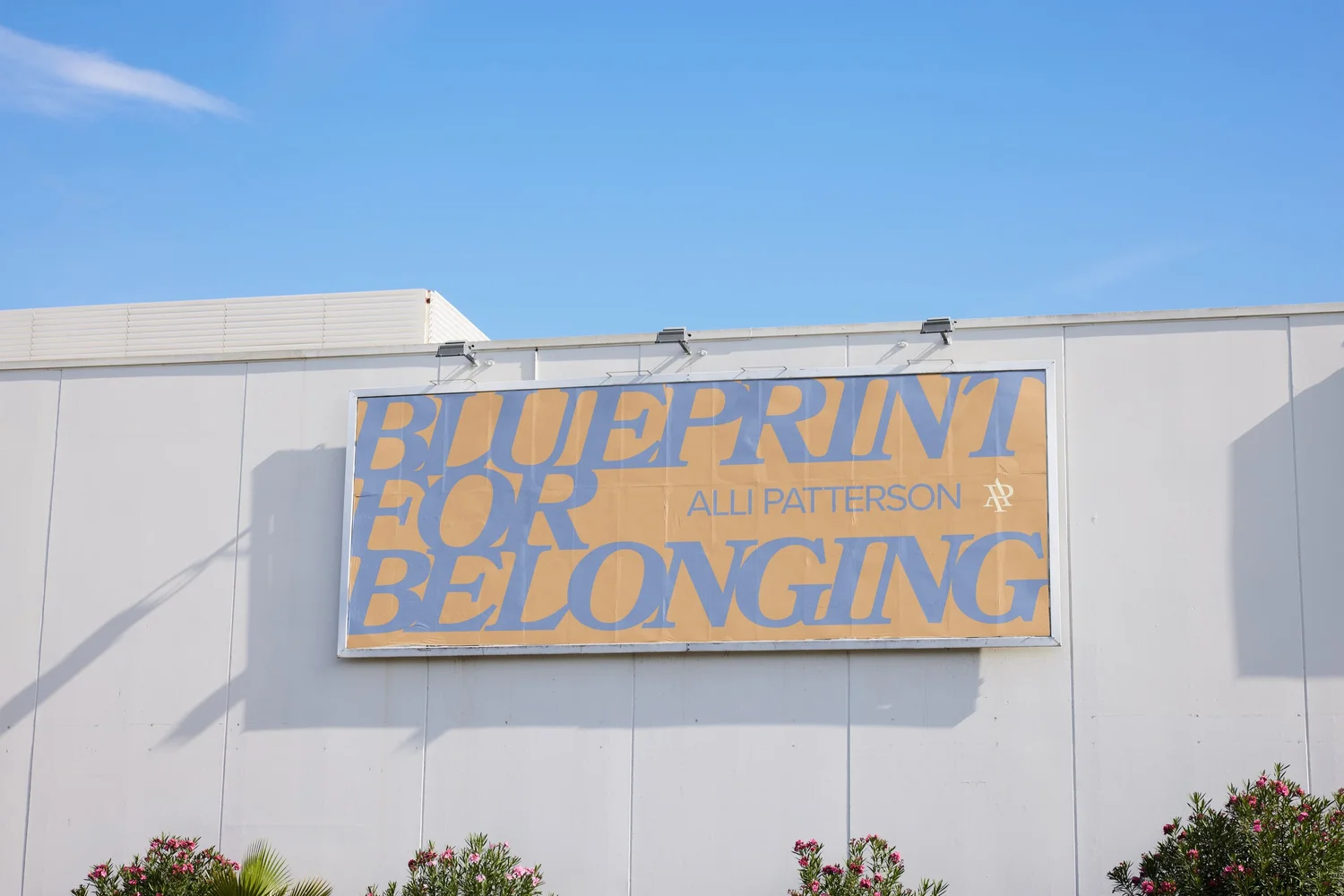 A Blueprint for Belonging banner on the side of a building, with the Alli Patterson wordmark
