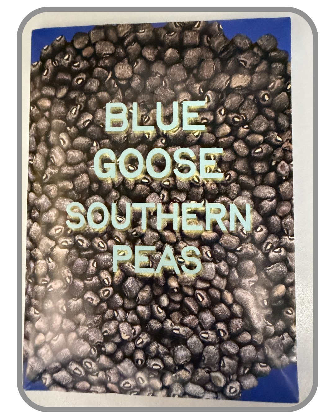 A collection of twelve heirloom seed packet images featuring vegetables grown by farmers and seed stewards in Western North Carolina. Each packet displays a close-up photograph of the crop variety and its name. The varieties include Blue Goose Southe
