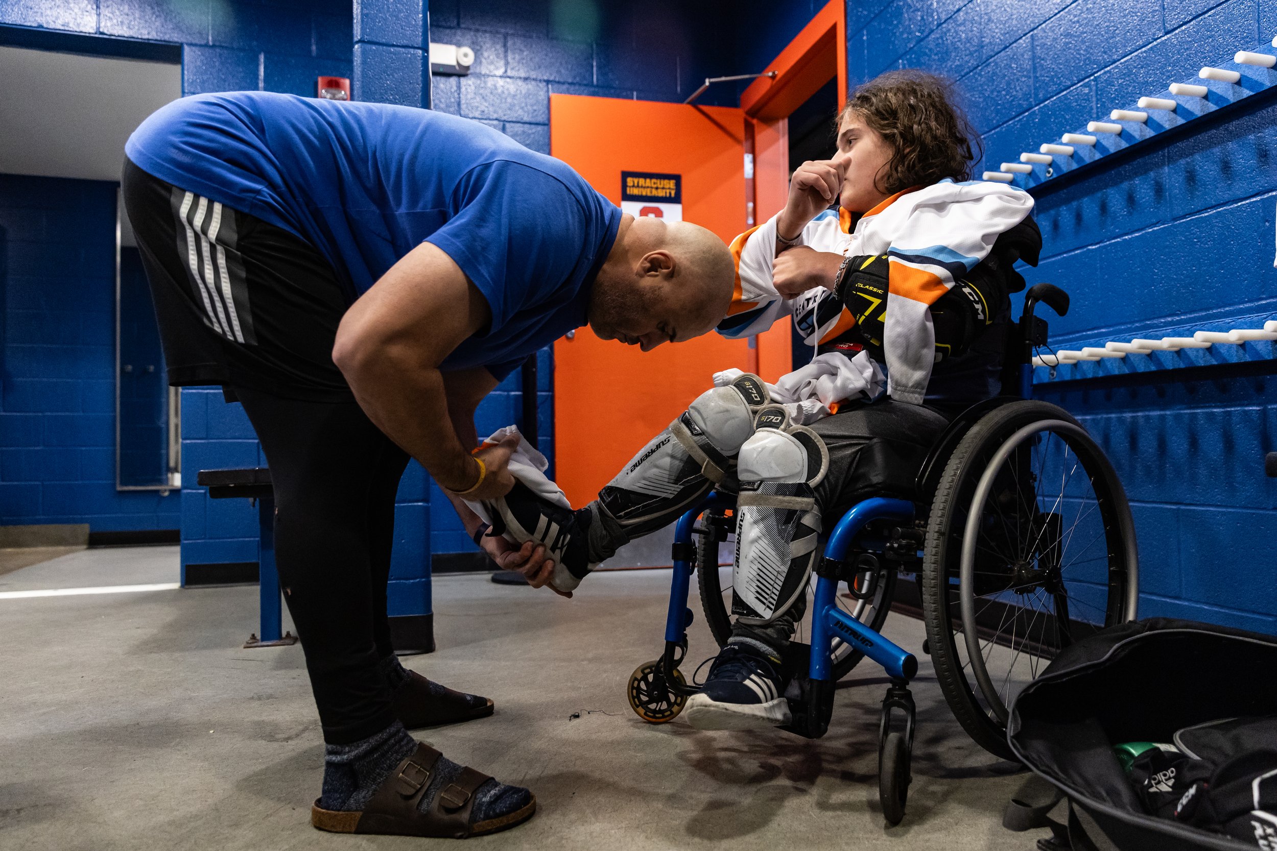 Jamie Favata helps his son, Myles Favata, put on his gear before their charity game against the Syracuse men’s club hockey team.
Myles fell in love with hockey at age three while watching a game on TV with his dad. After watching the Paralympics in