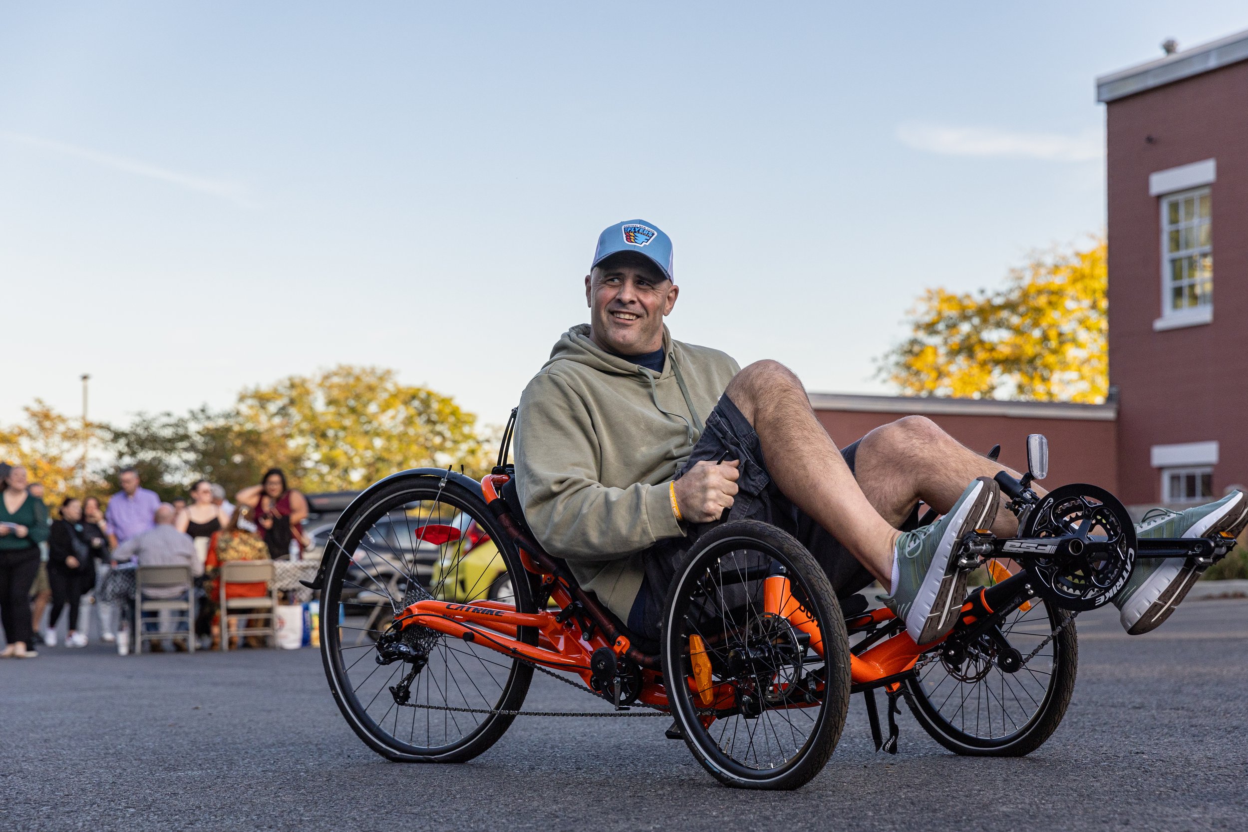 Jamie rides an adaptive bike, showing parents and students at The Jowonio School how it works.
Jamie’s advocacy for Myles extends far beyond sports. When Myles was younger, Jamie took on two groups of corporate lawyers to get bladder management serv