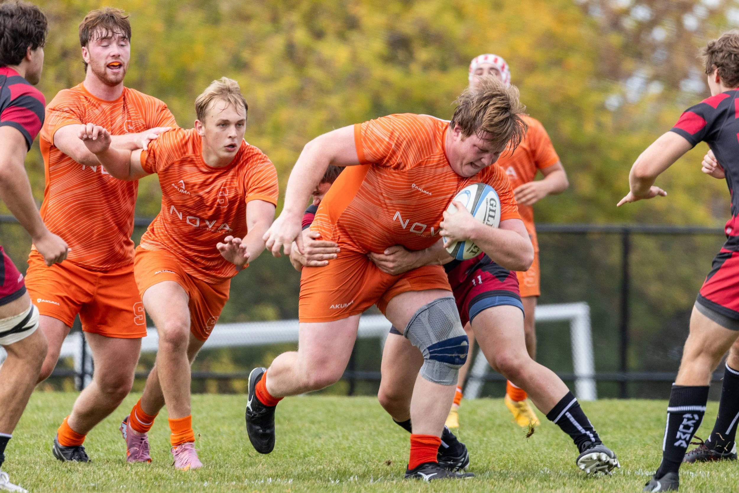 Syracuse club rugby senior captain pushes down the pitch as Harvard players attempt to stop him during their match on Oct.  18, 2025, at Ballentine Field. Despite getting a late start in rugby, he hasn’t allowed this to stop him from pursuing his pas