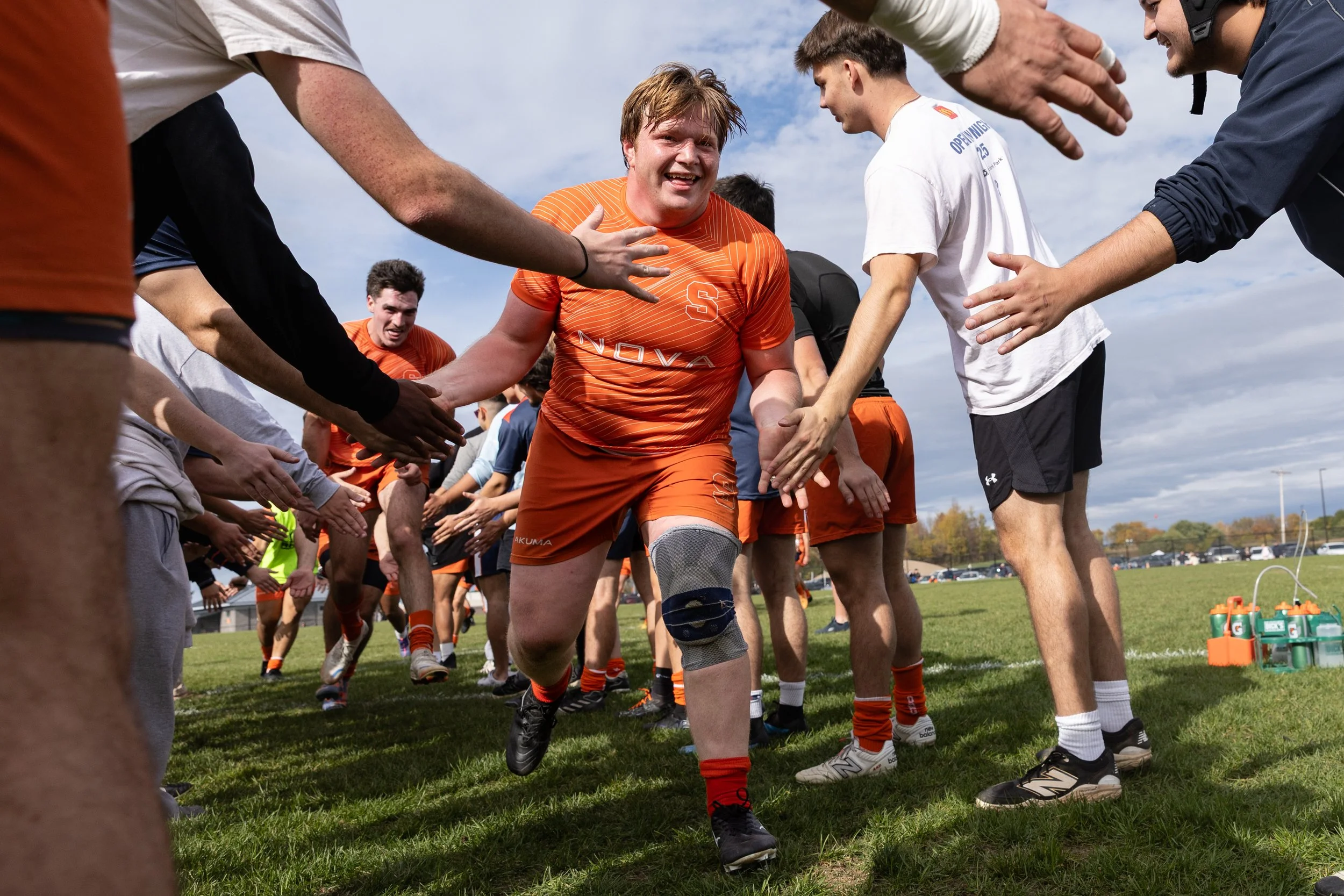 After a commanding victory against Harvard, SU club rugby captain Patrick Hefright runs through a tunnel of teammates to celebrate on Oct. 18, 2025, at Ballentine Field. Despite getting a late start in rugby, he hasn’t allowed this to stop him from p