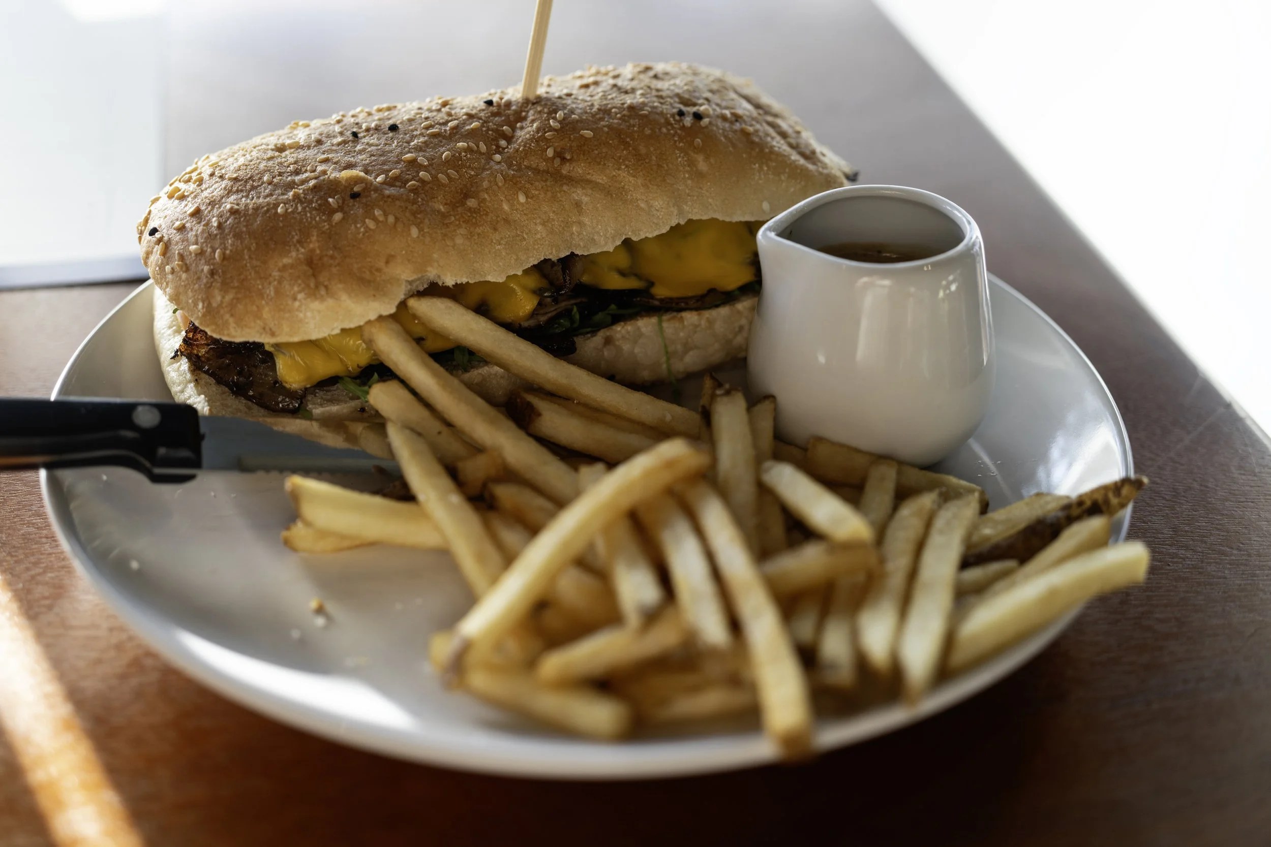 Cheesesteak sandwich with fries and sauce on white plate
