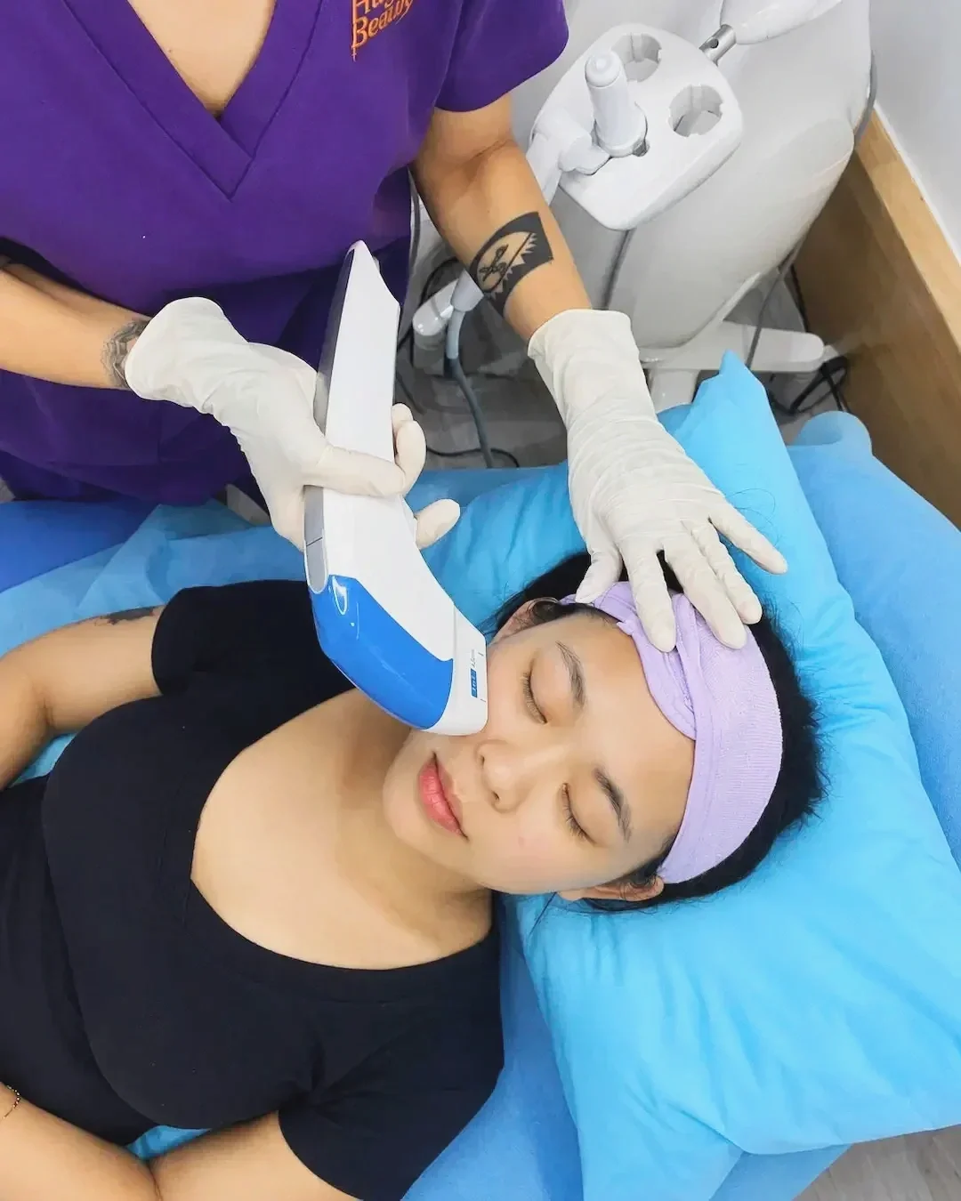 Gloved hands move the HIFU handpiece along a relaxed client’s jawline at Hugo Beauty, Ho Chi Minh City