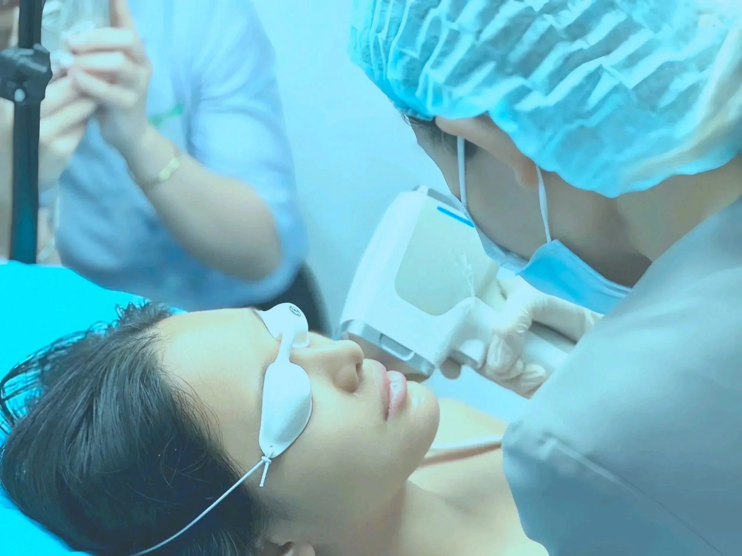 Medical professional in surgical attire performing a procedure on a patient.