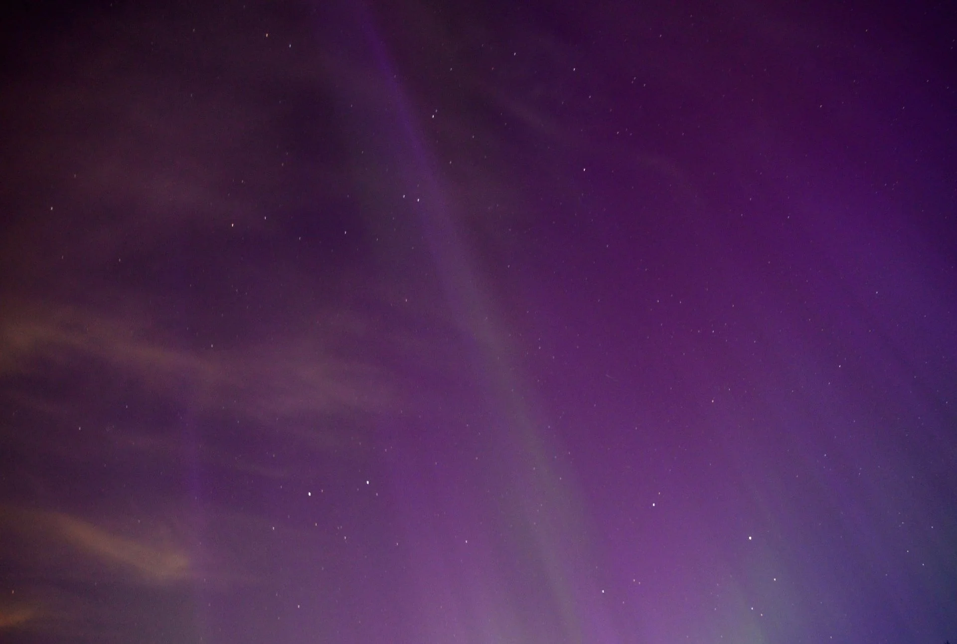 Northern Lights cast a magical violet glow in the sky, creating a mystical, serene atmosphere. The interplay of colours in the sky highlights it's natural and ethereal beauty.