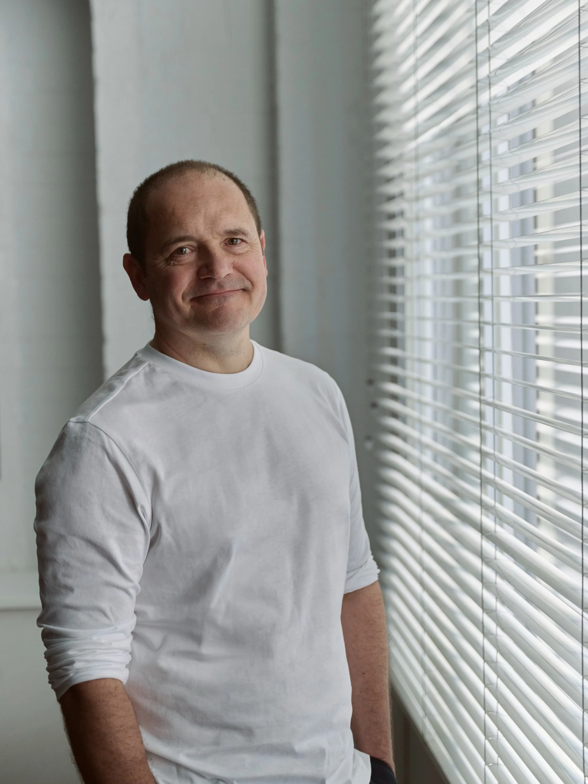 Harry Corsham Therapist in a white T shirt, by a window