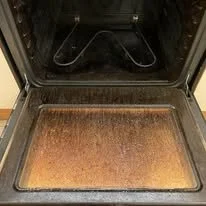 The inside of an oven with a heavily burnt and greasy oven rack and an oven floor with accumulated burnt debris.