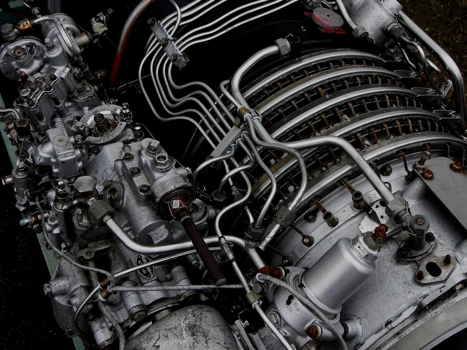 Close-up of a vintage aircraft engine with metal pipes, cylinders, and mechanical components.