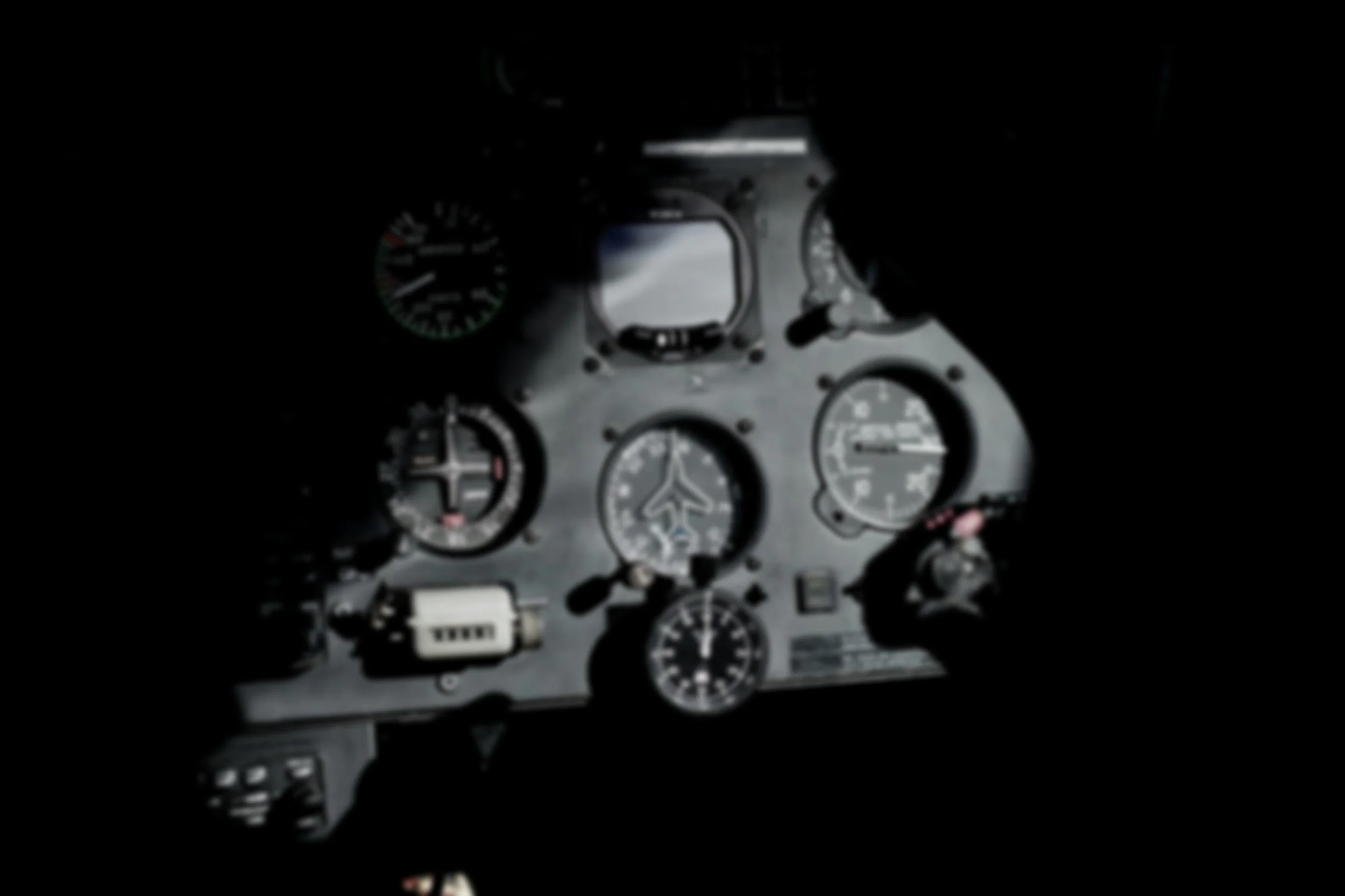 View of aircraft cockpit instruments and controls in low light.