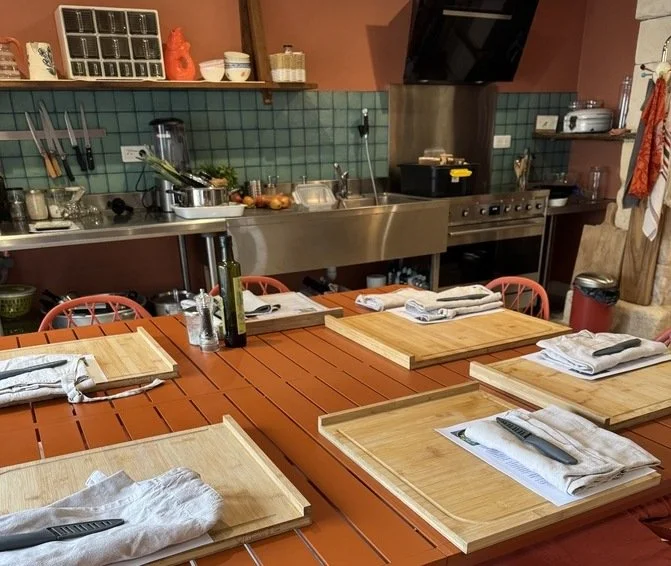 îlot atelier avec planche à découper couteau et tablier préparé pour 5 personnes dans une cuisine au ton orange et bleue