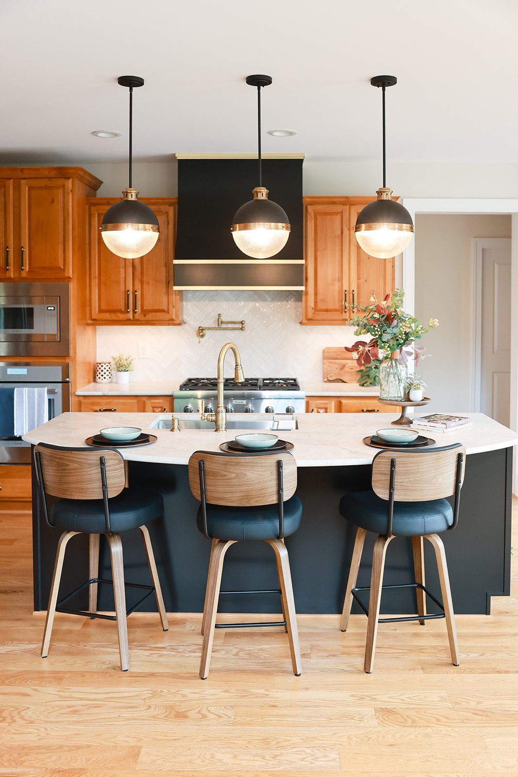 Kitchen refresh reveal ✨

The warmth of the existing wood cabinetry provided the foundation for this refresh. To create contrast and add depth, we painted the island black and incorporated black accents throughout the space, including a statement hoo