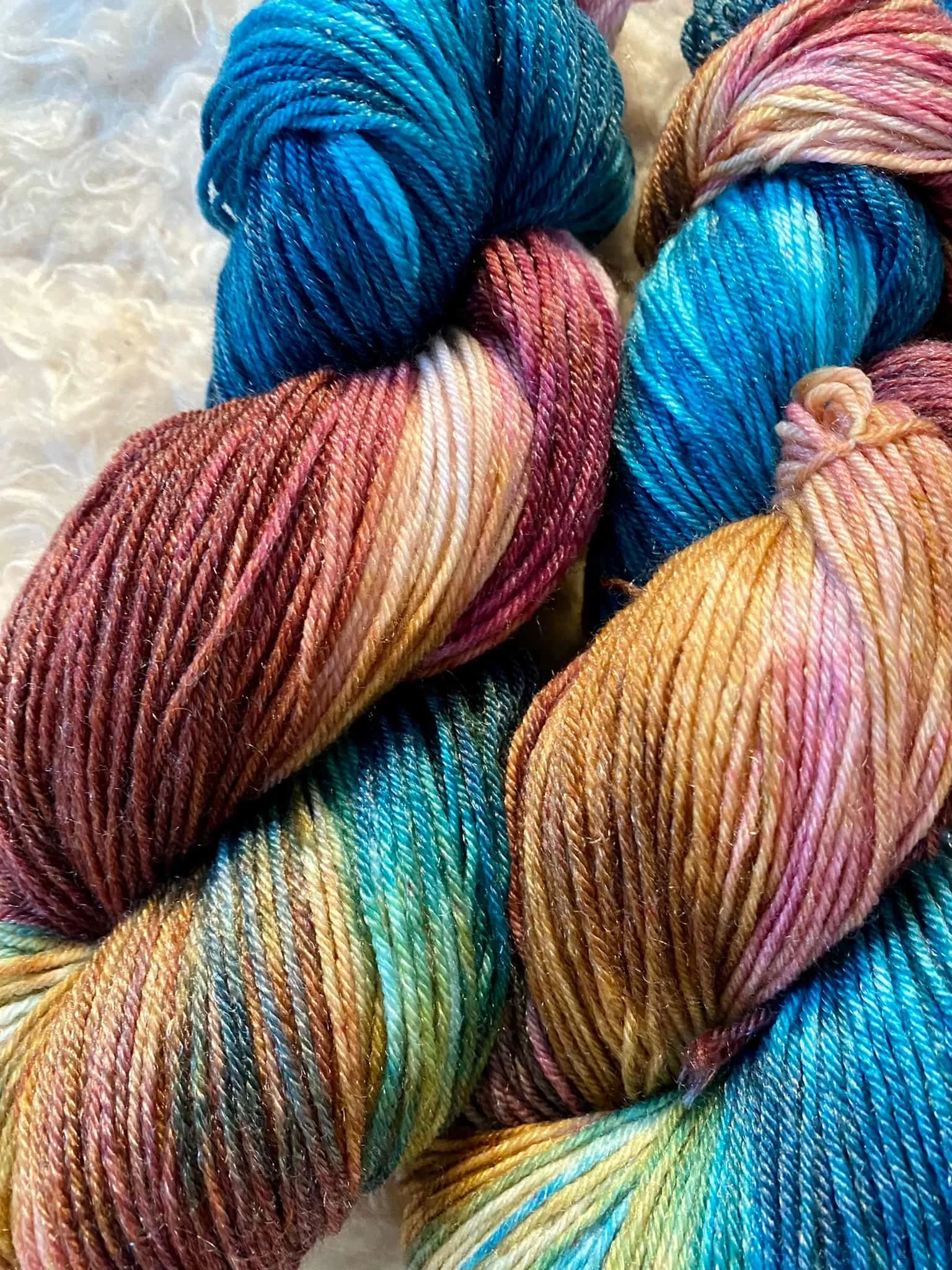 Bunte, gedrehte Strickgarne in Blau, Rosa, Gelb und Grün Tönen.