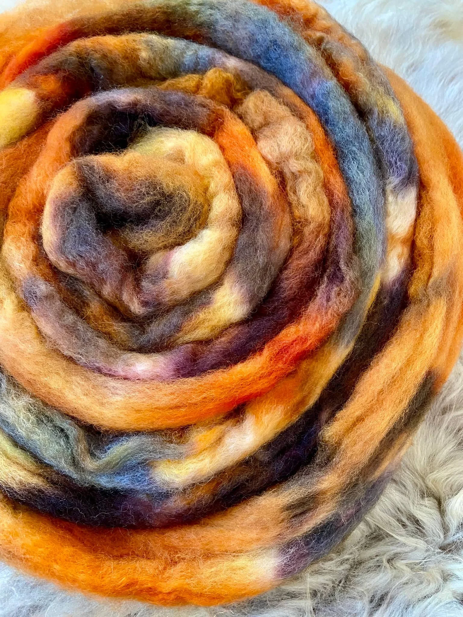 Bunte, gefilzte Wollstränge in verschiedenen Farben, auf einer weichen Oberfläche.