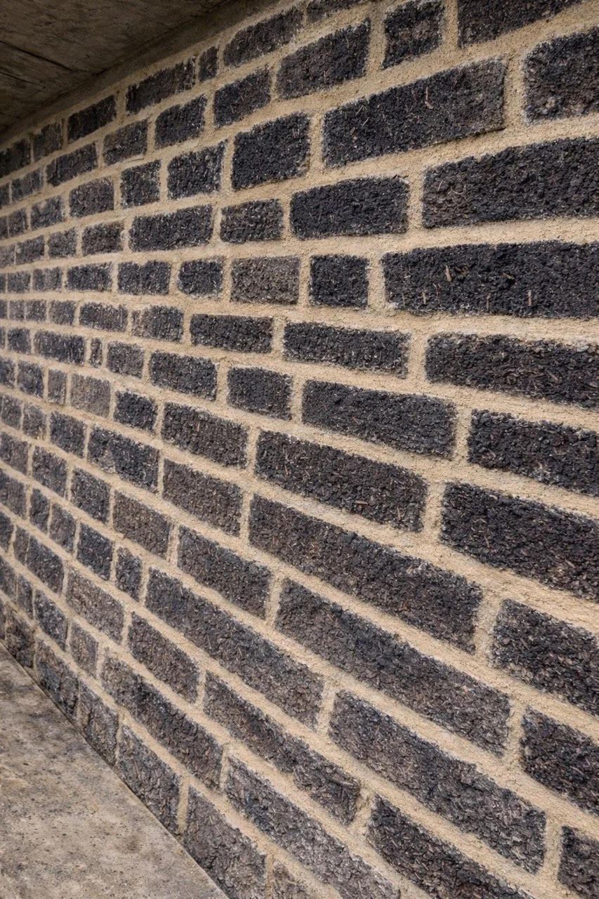 Close-up view of a brick wall with dark brown bricks and light mortar.