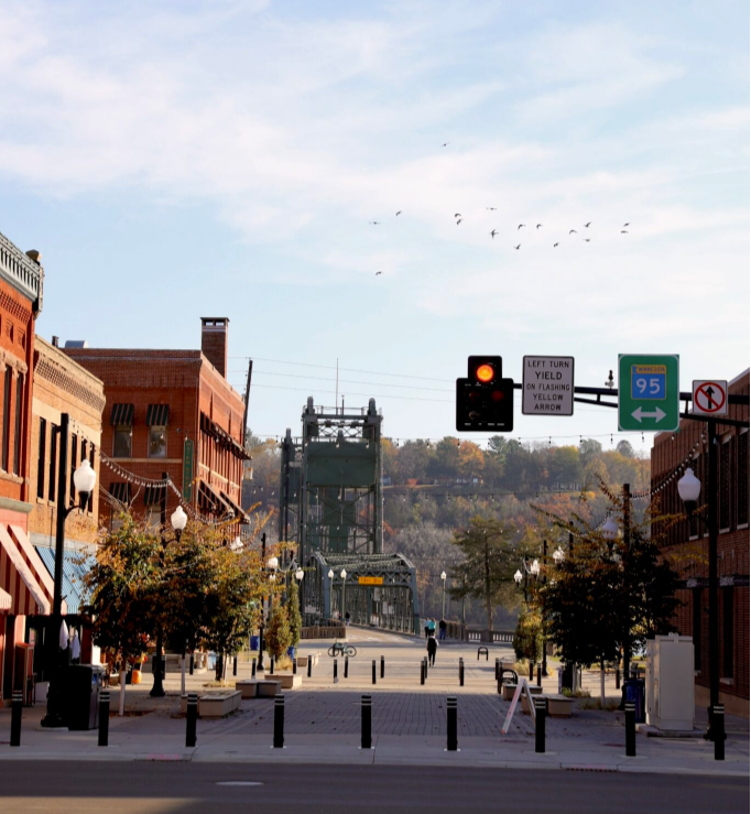 Downtown Stillwater, Minnesota with a bridge in the background, traffic lights, and colorful buildings on either side.