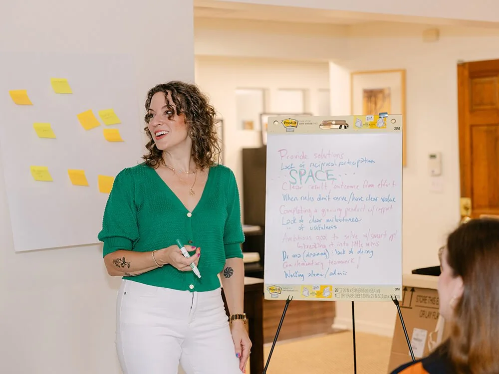 Photo of Cat in action, using a dry erase board and sticky notes while running a workshop