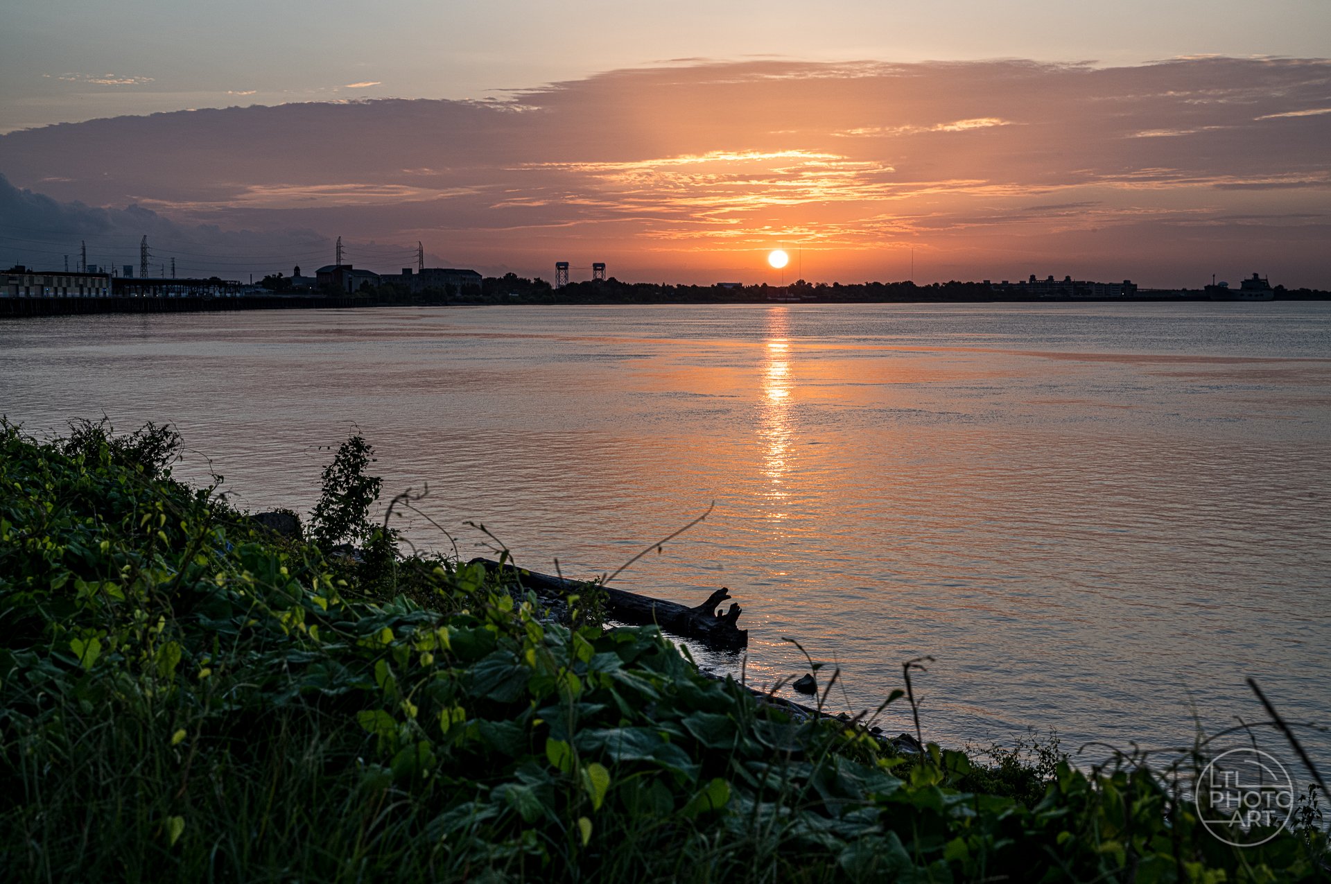 Sunrise over the Mississippi River in New Orleans, with warm orange light reflecting on the water near the bend that gives the city its Crescent City name.