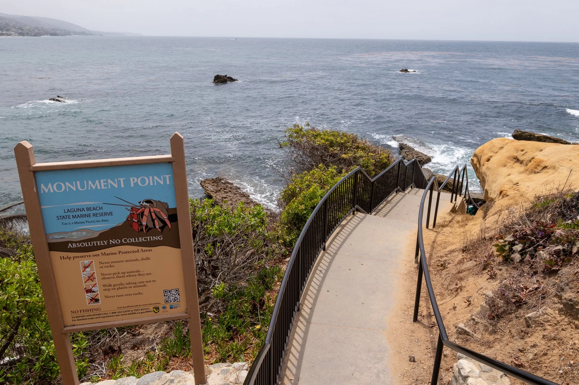 Stairs leading down from Monument Point in Laguna Beach toward the rocky shoreline and Pacific Ocean.
