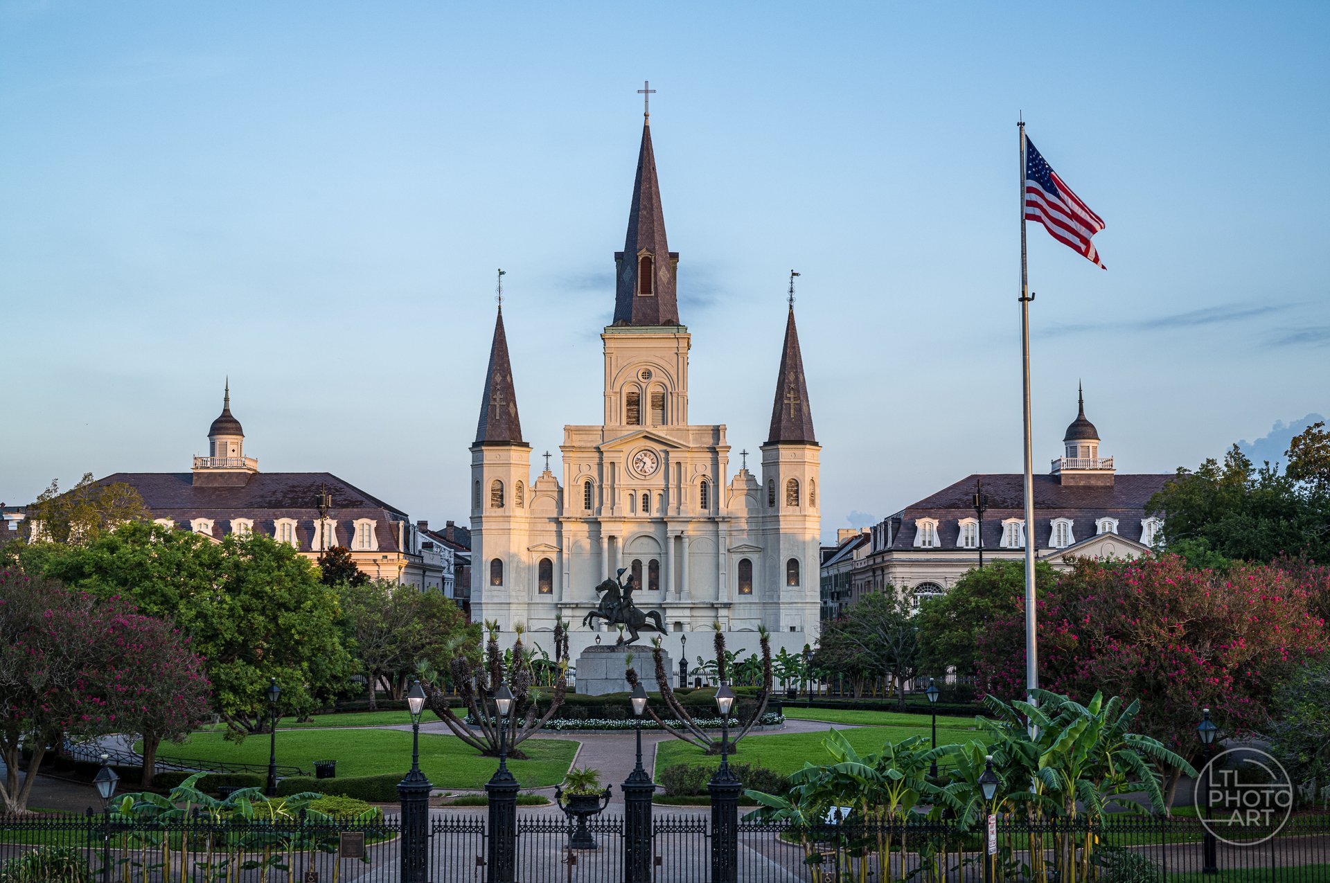 St. Louis Cathedral viewed from Jackson Square in New Orleans, with the Andrew Jackson statue, American flag, gardens, and morning light.