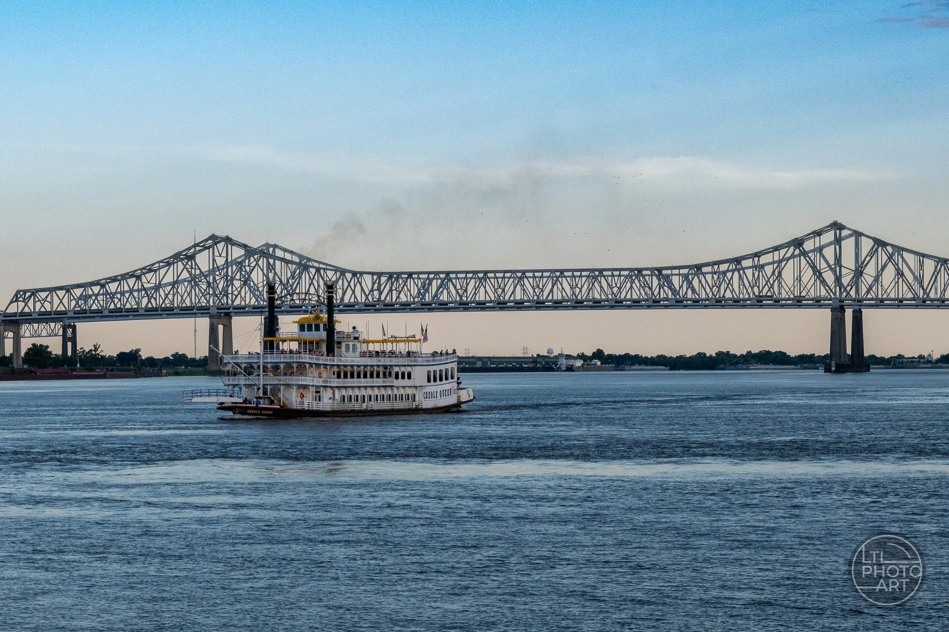 Crescent City Connection bridge over the Mississippi River in New Orleans, with a riverboat passing beneath the steel span.