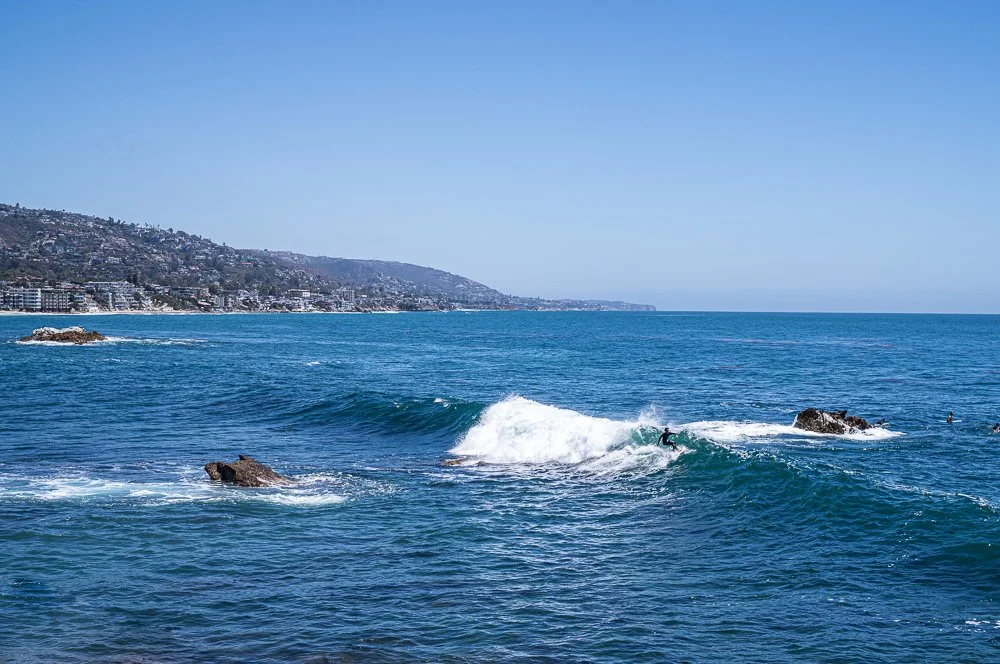 Surfer riding a breaking wave along the Laguna Beach coastline, illustrating the dynamic coastal scenes and action photography opportunities explored during the LTL Photo Art Coastal Photography Workshop.
