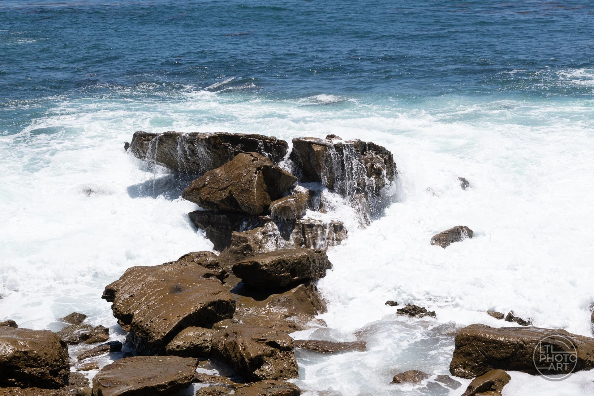 Waves breaking over rocks at Monument Point in Laguna Beach, creating motion, texture, and coastal detail.