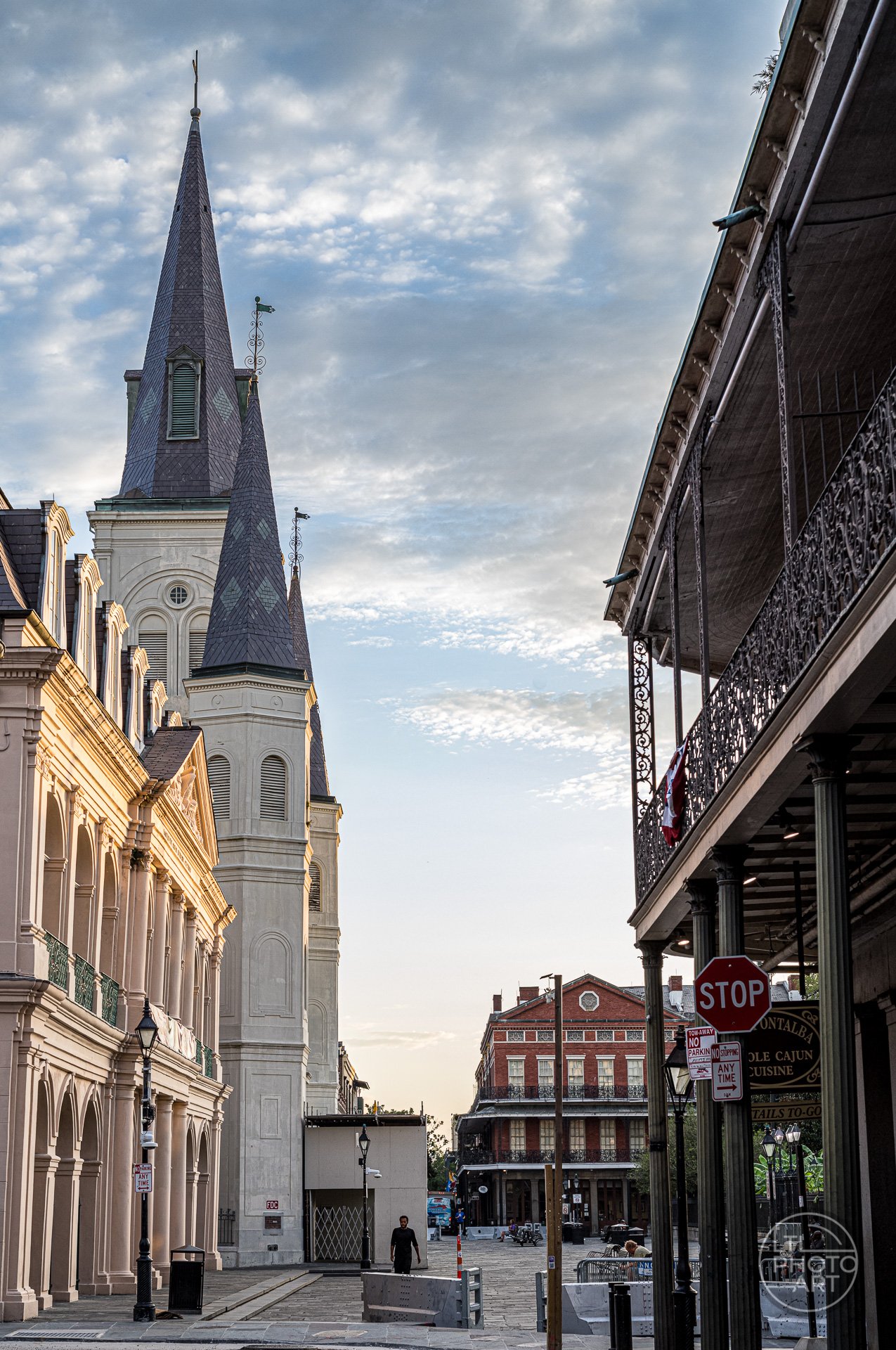 The Cabildo Museum and St. Louis Cathedral viewed from Chartres Street in New Orleans, framed by surrounding buildings and early light.