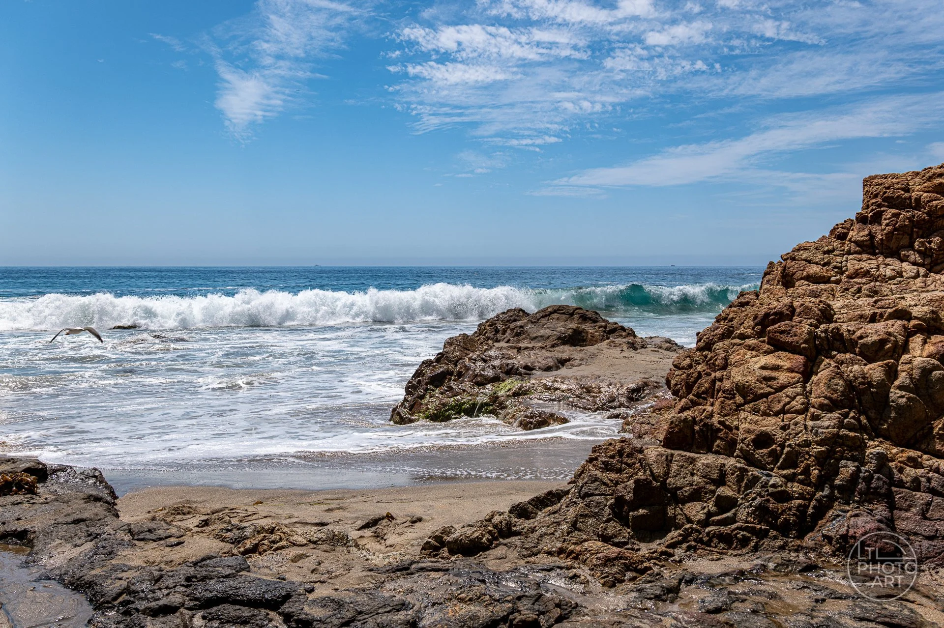 Sea-level view of Rockpile Beach with textured coastal rocks, breaking waves, and the Pacific Ocean in Laguna Beach, California.