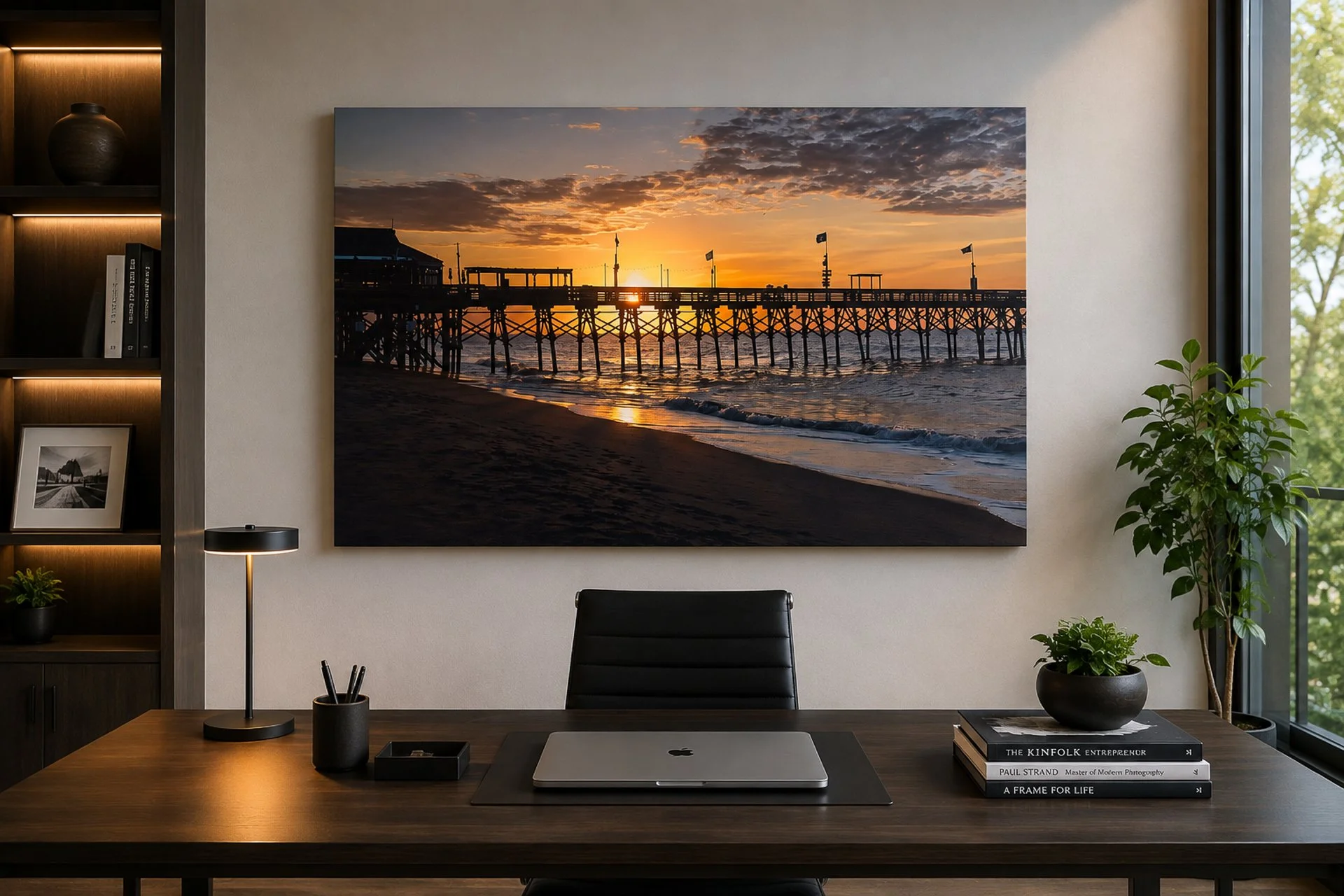 Large fine art photograph of a pier at sunrise displayed above a desk in a modern office.