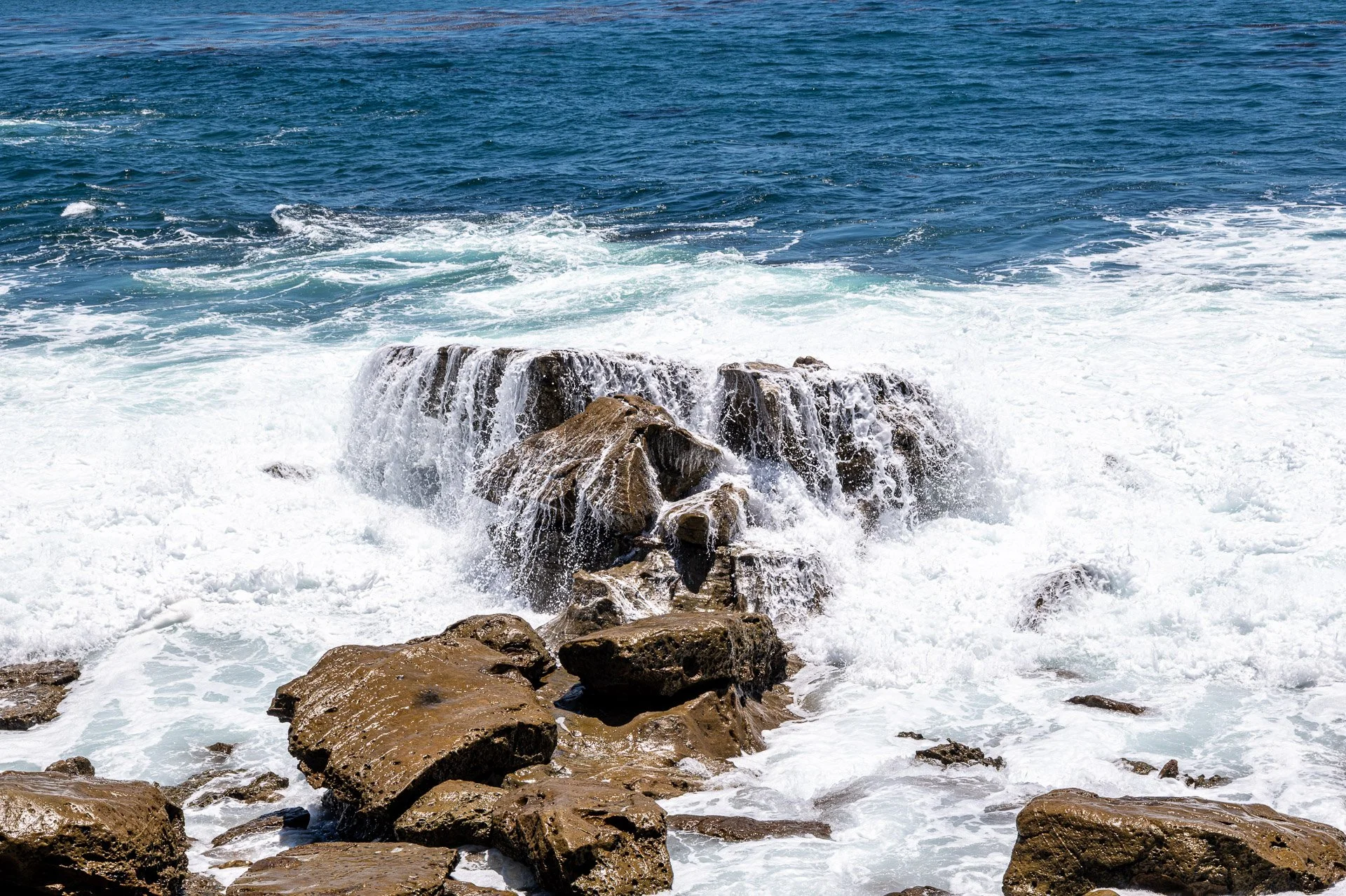 Water cascading over rocks at Monument Point in Laguna Beach after a wave passes through the scene