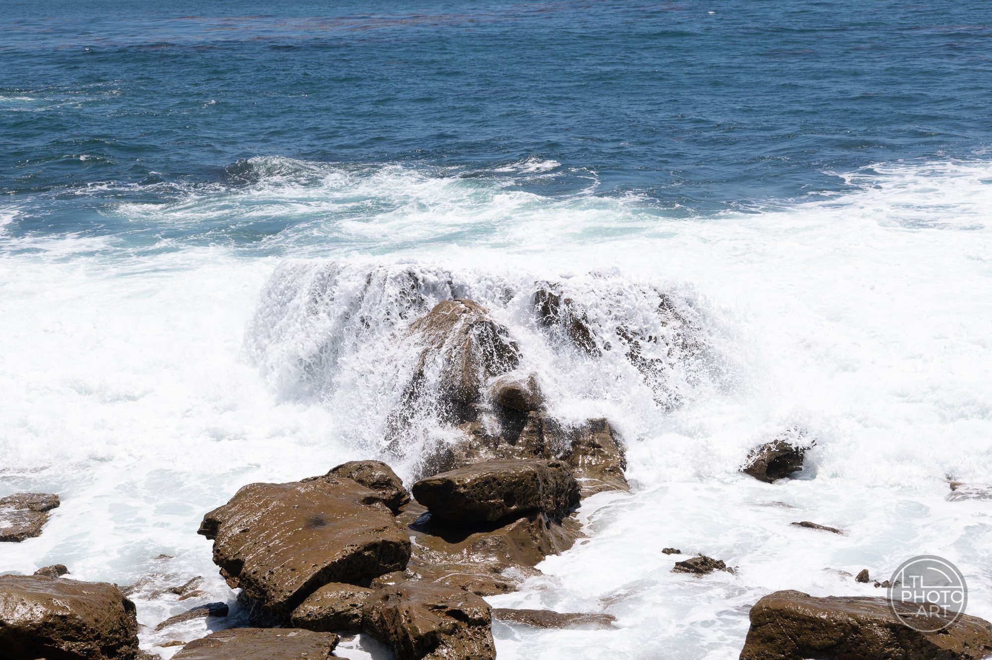 Water cascading over rocks at Monument Point in Laguna Beach, photographed at 1/350 second and ISO 280 after a wave moved through the scene.