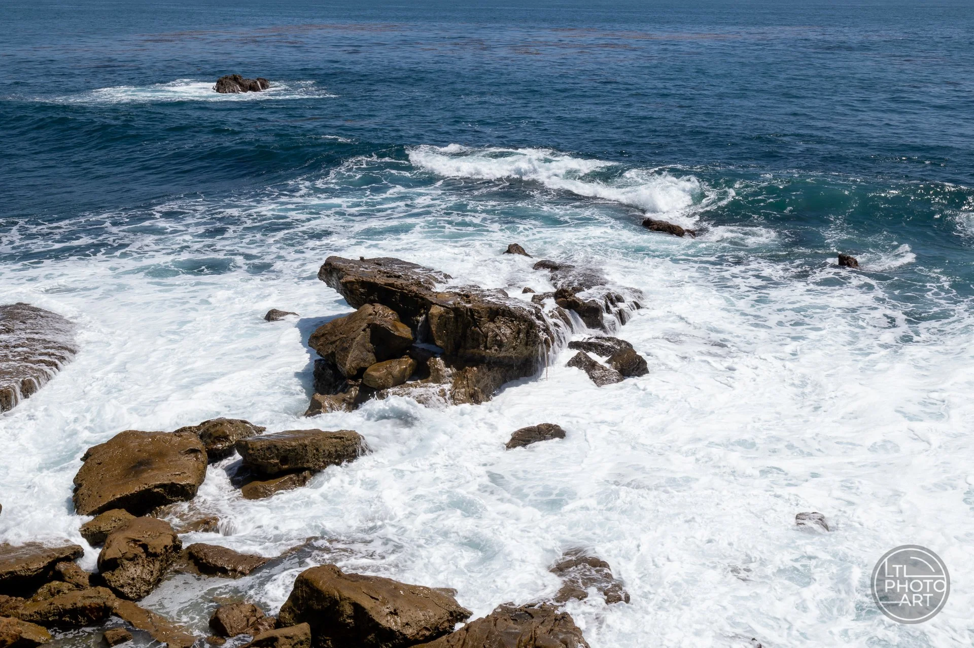 An elevated view above Monument Point shows how shutter speed can shape the feeling of moving water, turning waves and foam into softer patterns around the rocks.