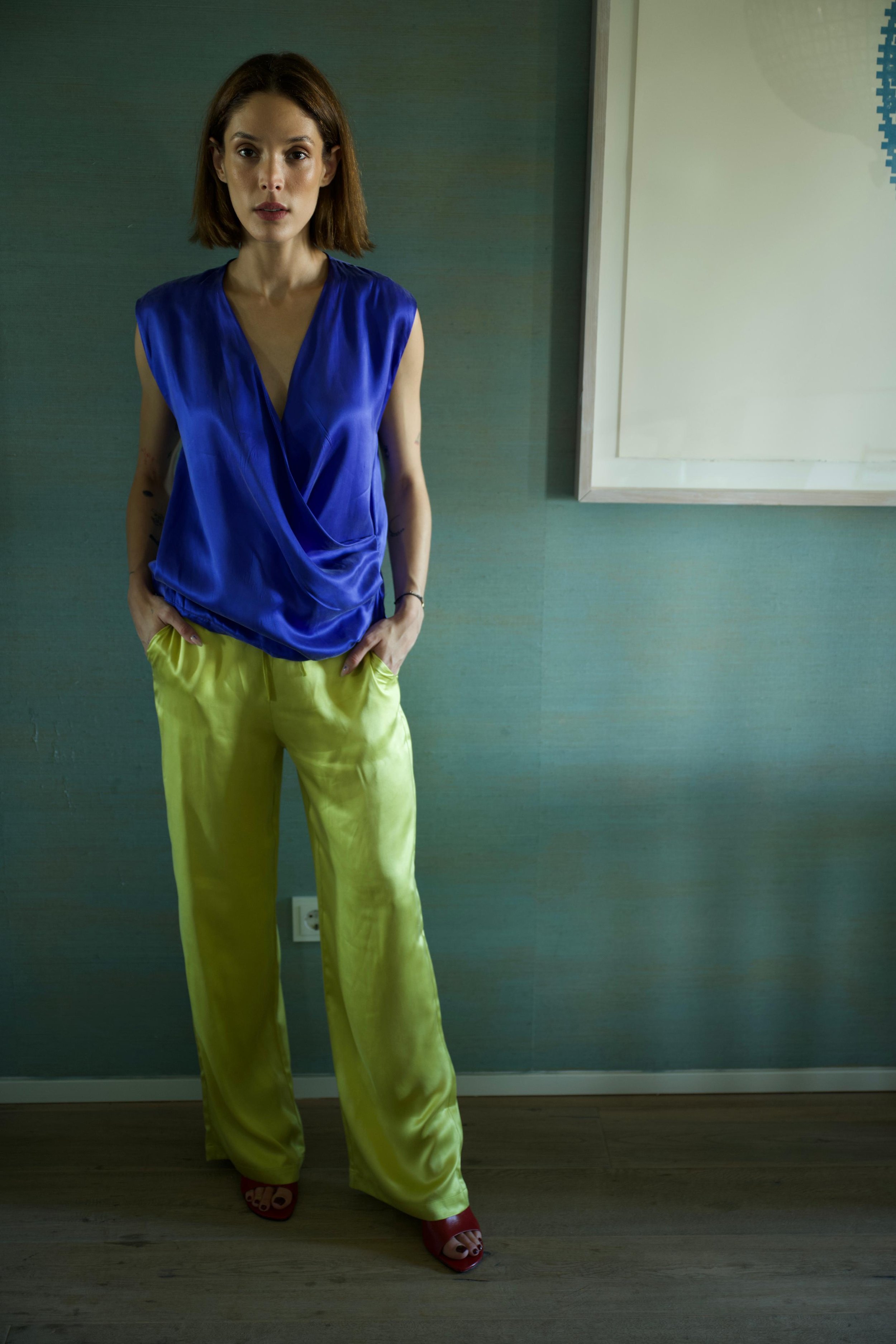 Woman wearing green silk pants and blue draped top