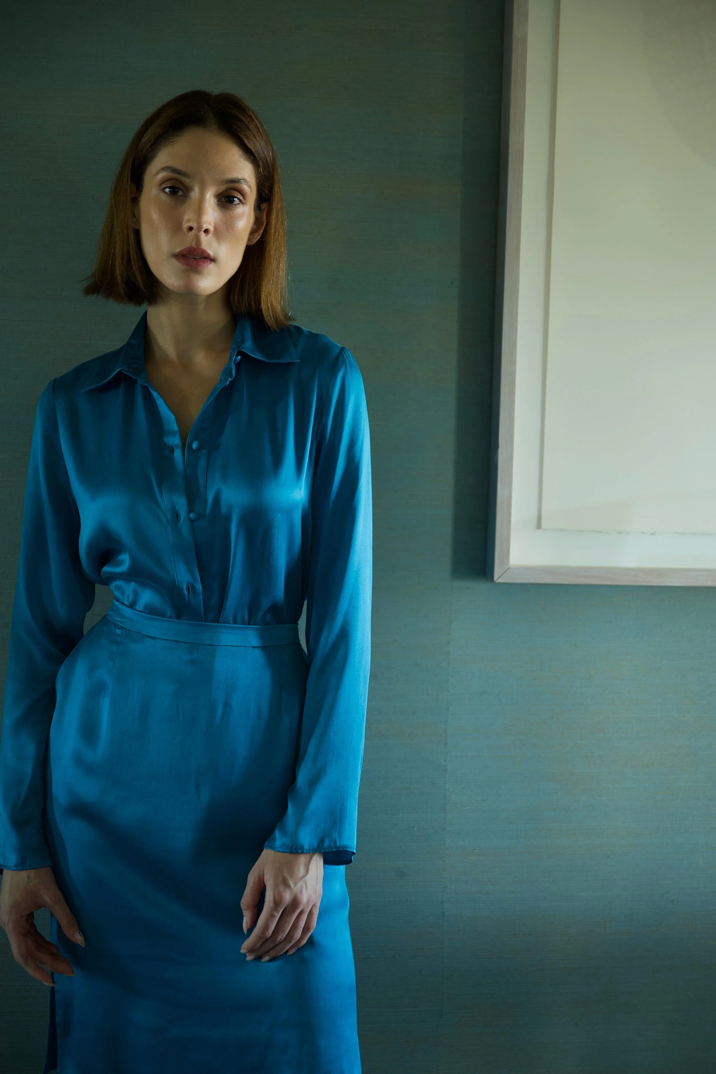 Woman wearing turquoise silk shirt and matching skirt