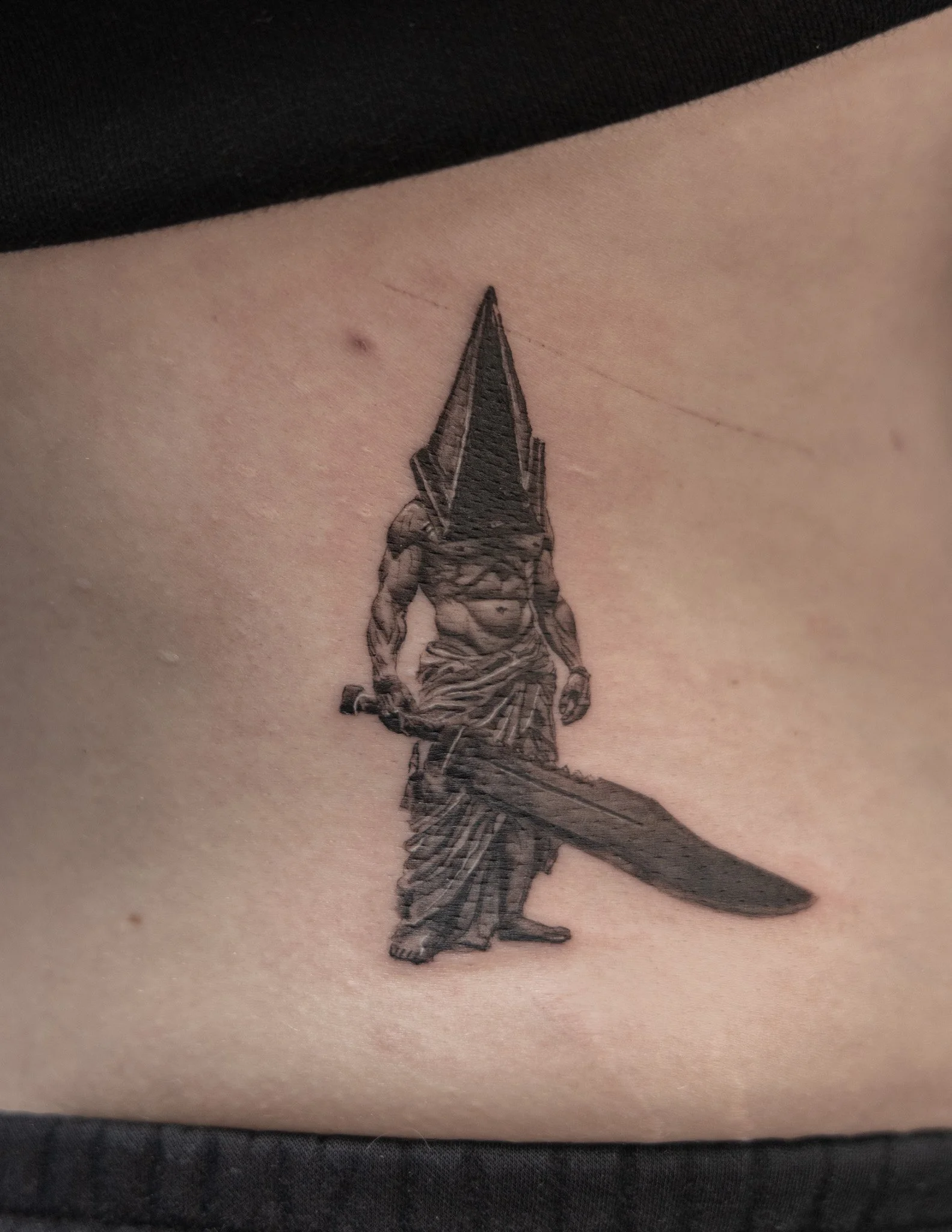 Tattoo of a warrior with a sword, carrying a large spear on a person's side.