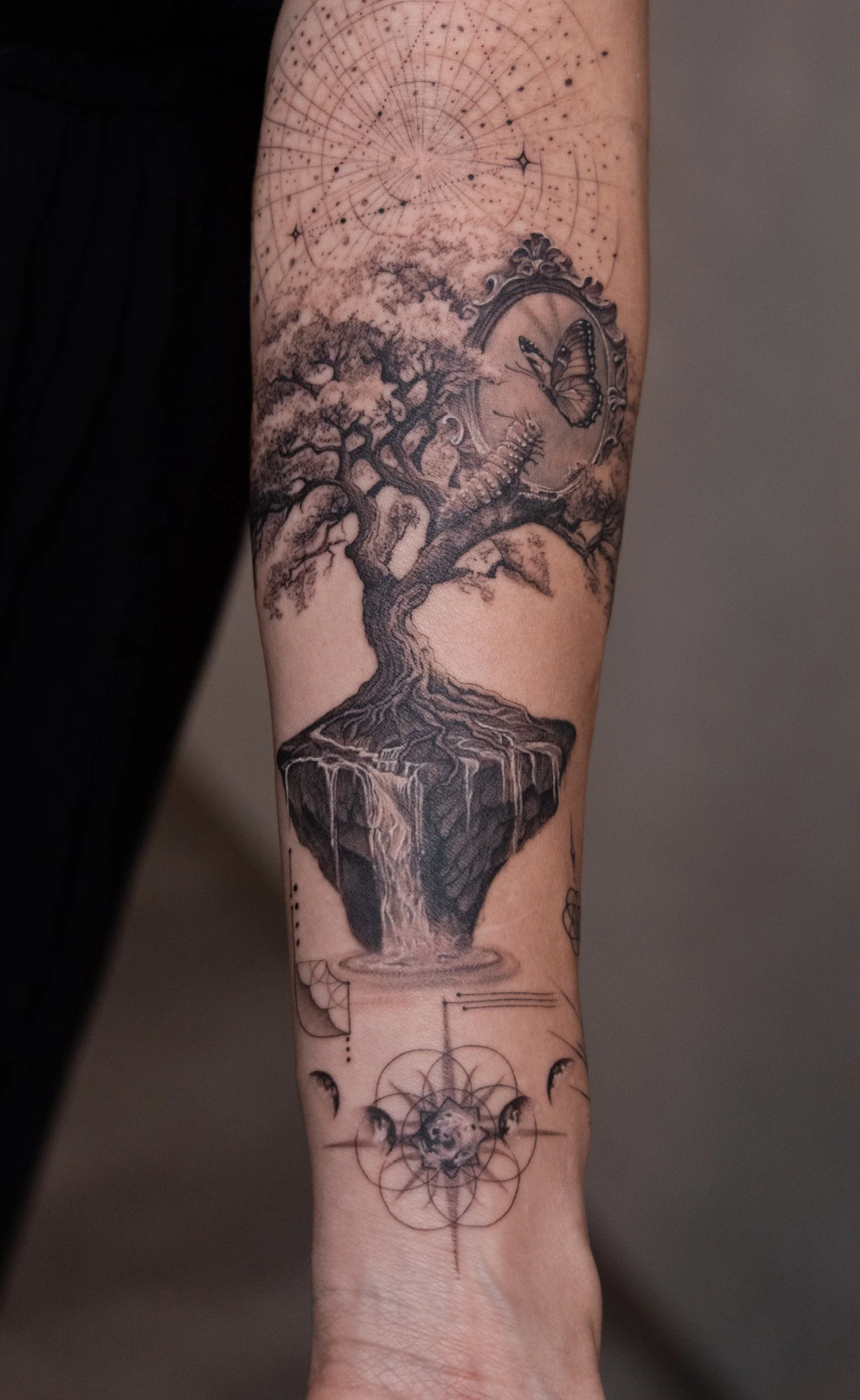 Tattoo of a floating island with a waterfall, a large tree, a butterfly, and celestial elements on a person's forearm.