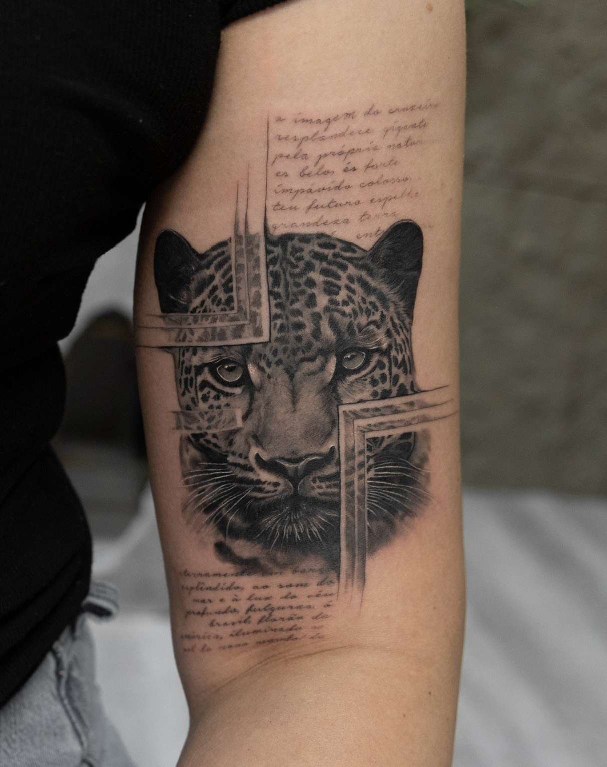 Tattoo of a leopard's face with geometric frame and handwritten text surrounding it.