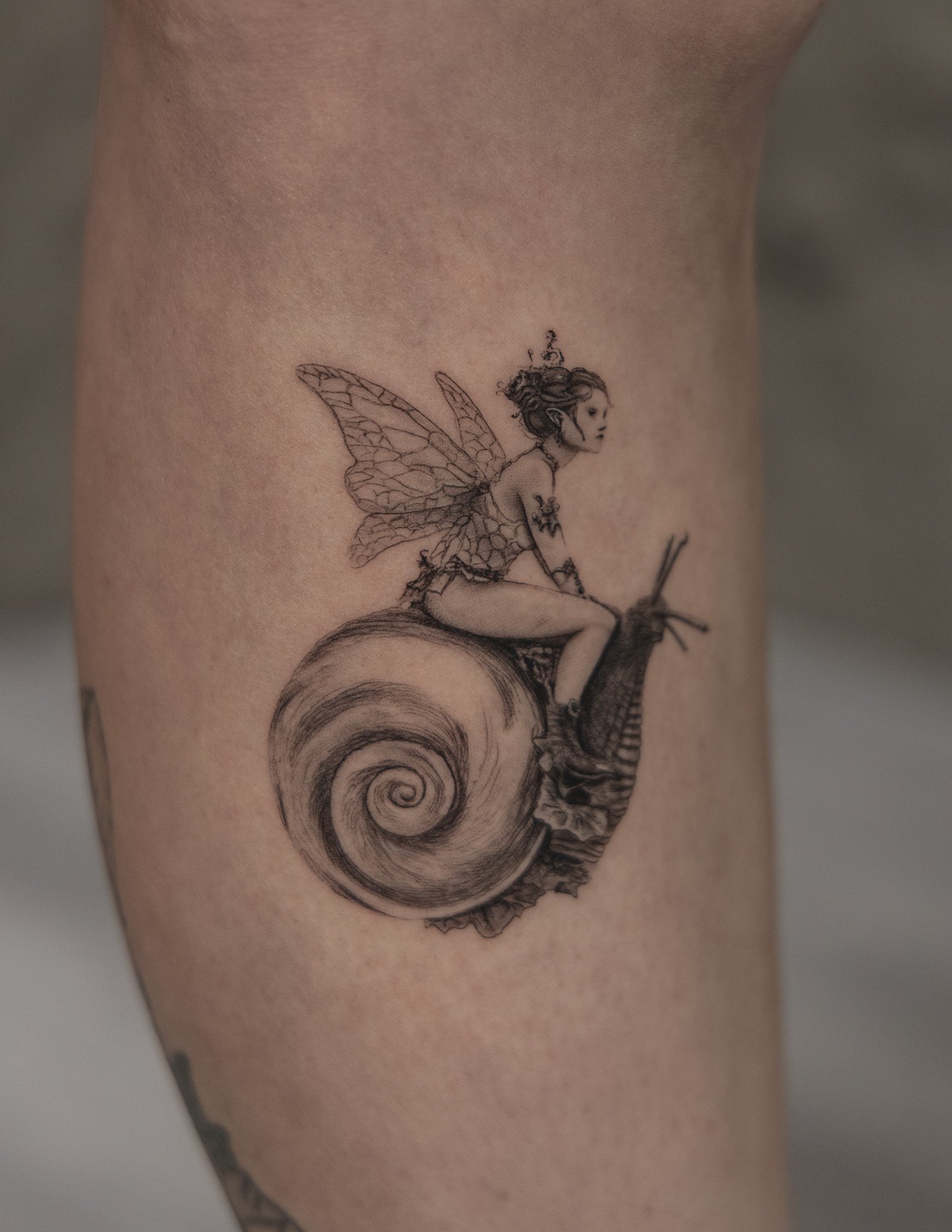 Tattoo of a fairy with butterfly wings riding a snail on skin.
