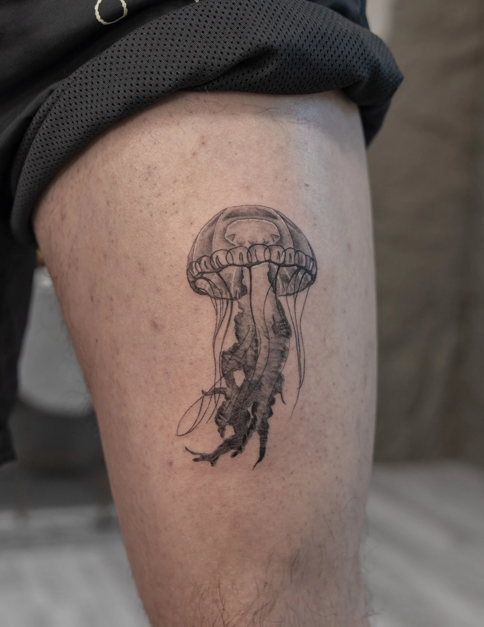 Tattoo of a jellyfish on a person's upper thigh.