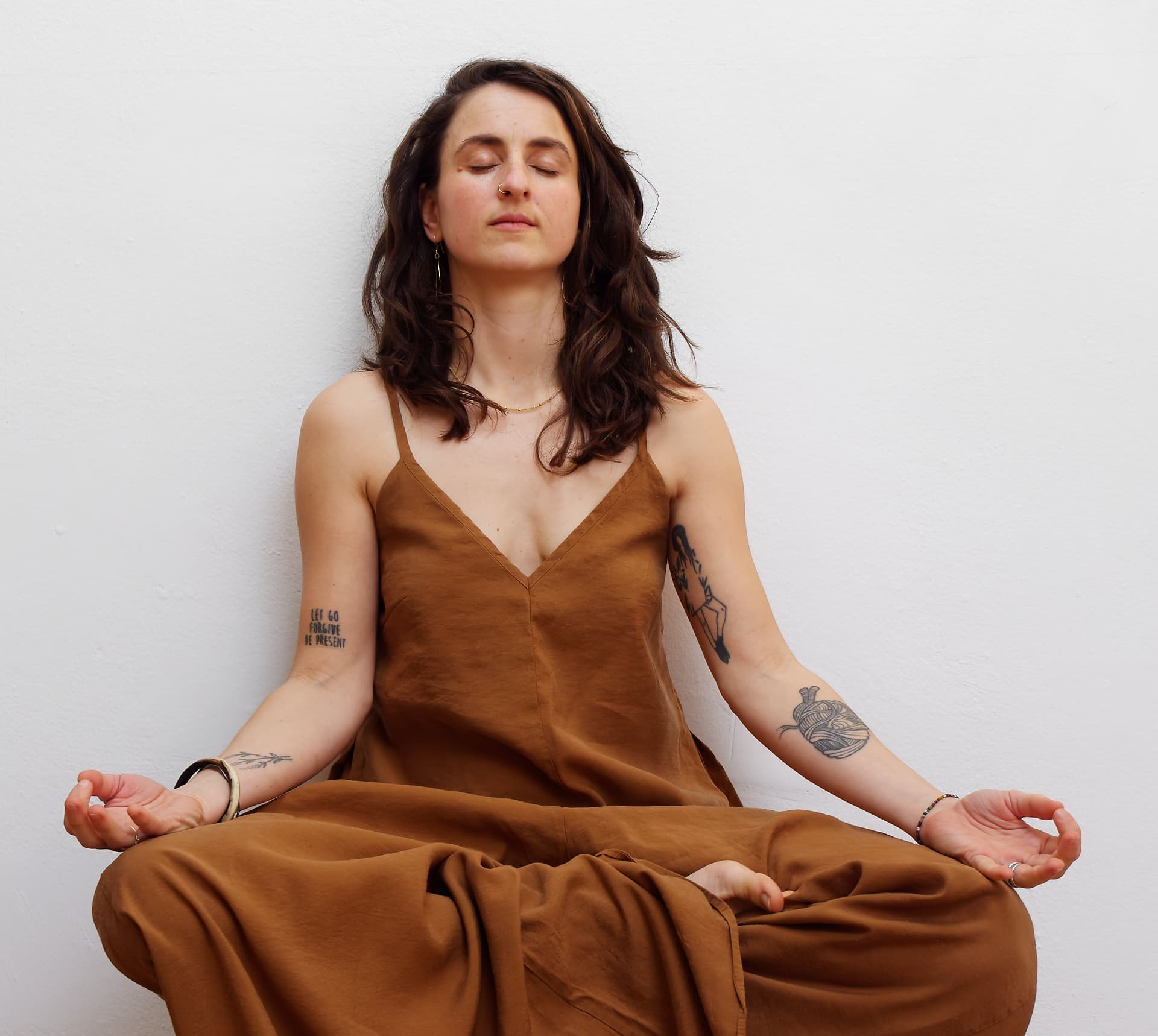 Eine Frau in einer meditativen Yoga-Sitzhaltung in einem hellen Raum, Fokus auf Ruhe und Selbsterkenntnis als Kontrast zu schnellen Fitness-Trends wie Pilates.